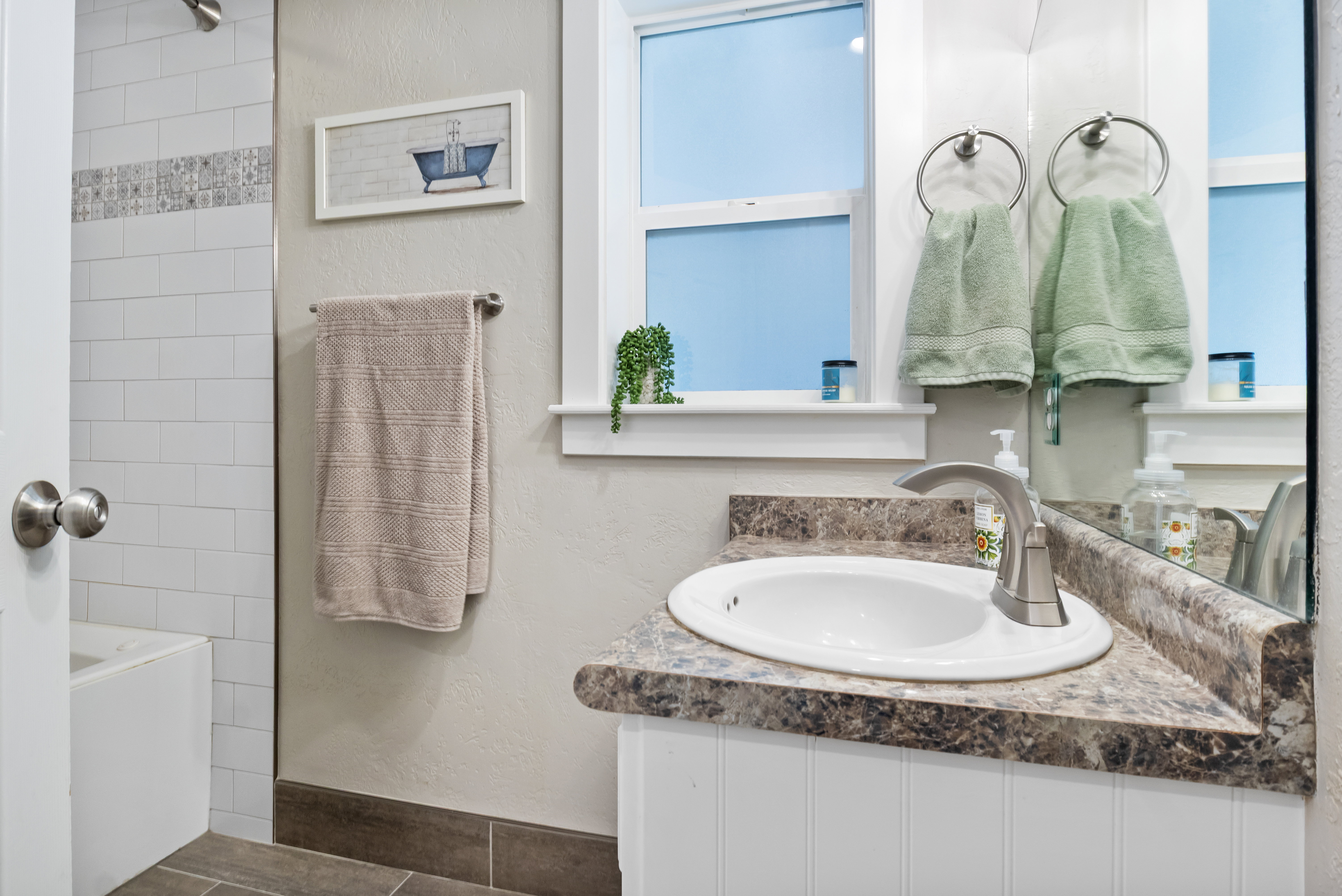 Bathroom vanity with an integrated sink, brushed nickel faucet, and a patterned countertop