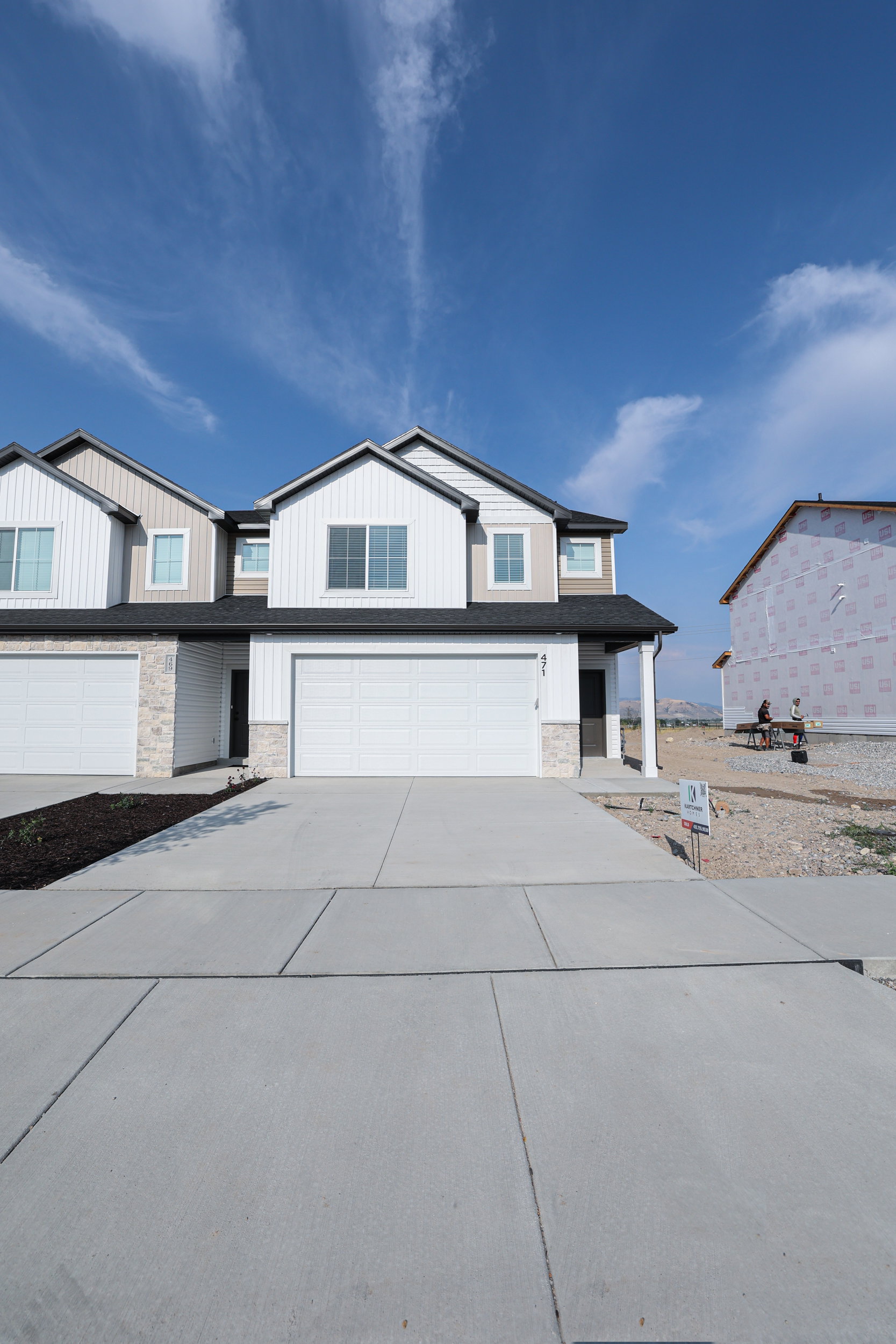 Modern multi-level townhome featuring white siding, dark trim accents, and a dark shingle roof
