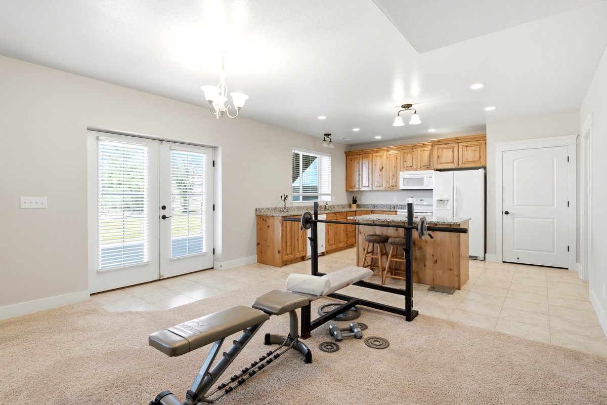 Bright interior space with French doors and a full kitchen featuring wood cabinetry, white appliances, and a kitchen island with seating