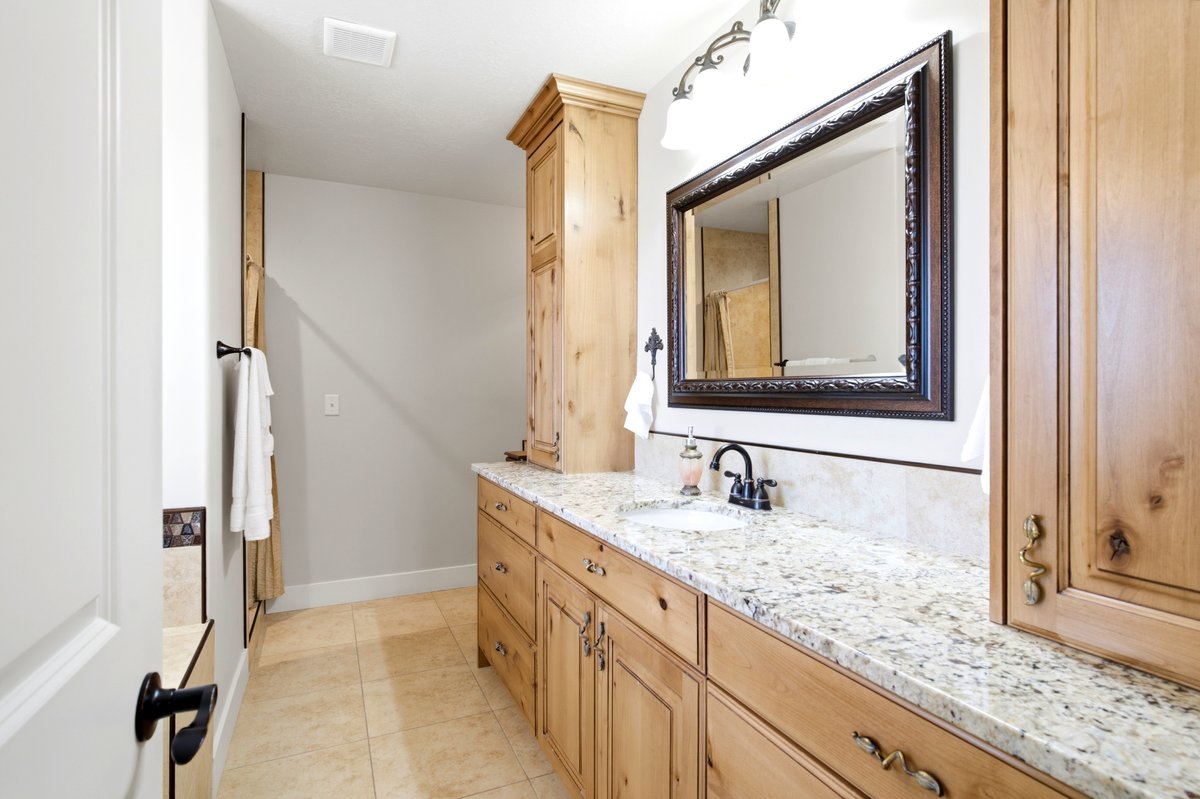 Bathroom vanity featuring light-toned wood cabinetry, a speckled granite countertop, and an undermount sink
