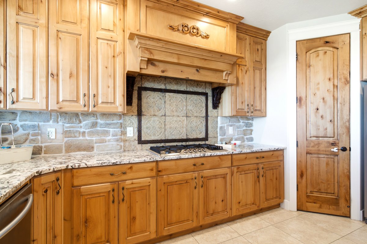 Kitchen featuring wood-finish cabinetry, granite countertops, and a stone-tile backsplash