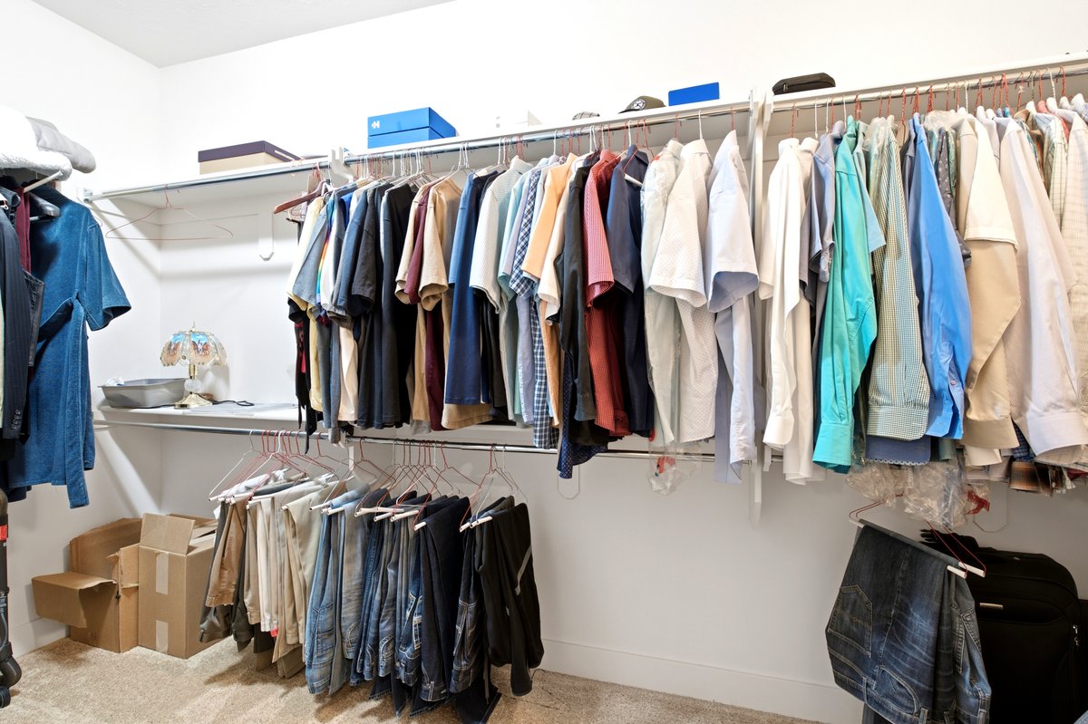 Walk-in closet featuring built-in shelving, multiple hanging rods, and carpet flooring