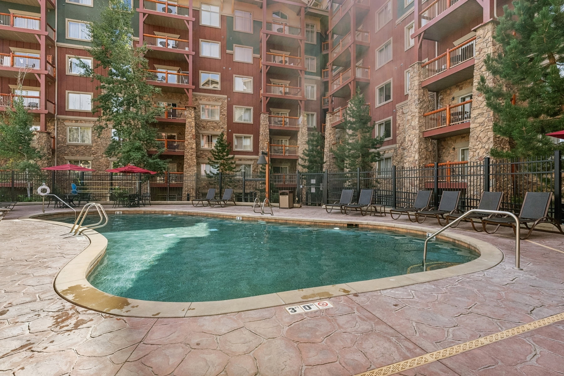 Outdoor swimming pool featuring a curved design and surrounding stamped concrete decking