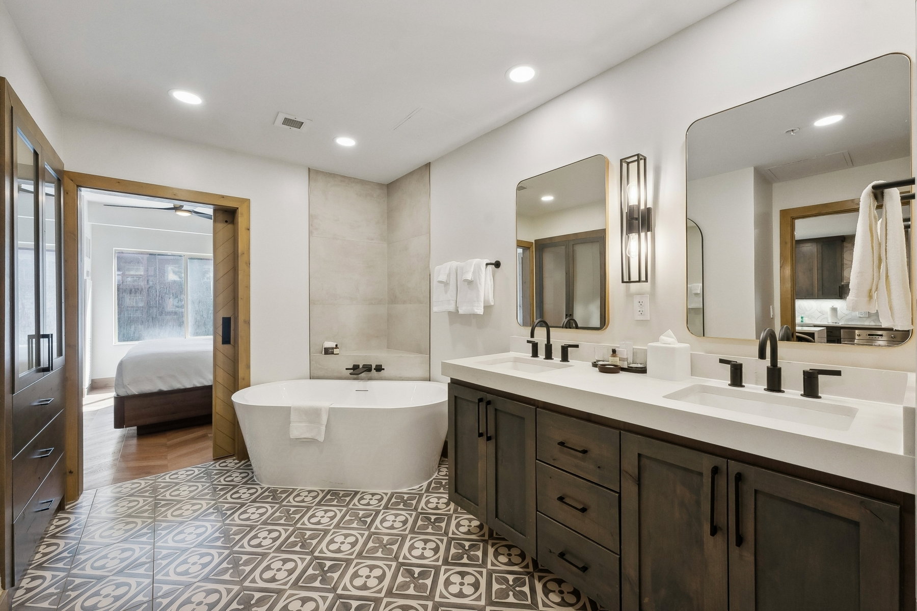 Bathroom featuring a freestanding soaking tub, dual vanity with undermount sinks, patterned floor tile, and matte black fixtures
