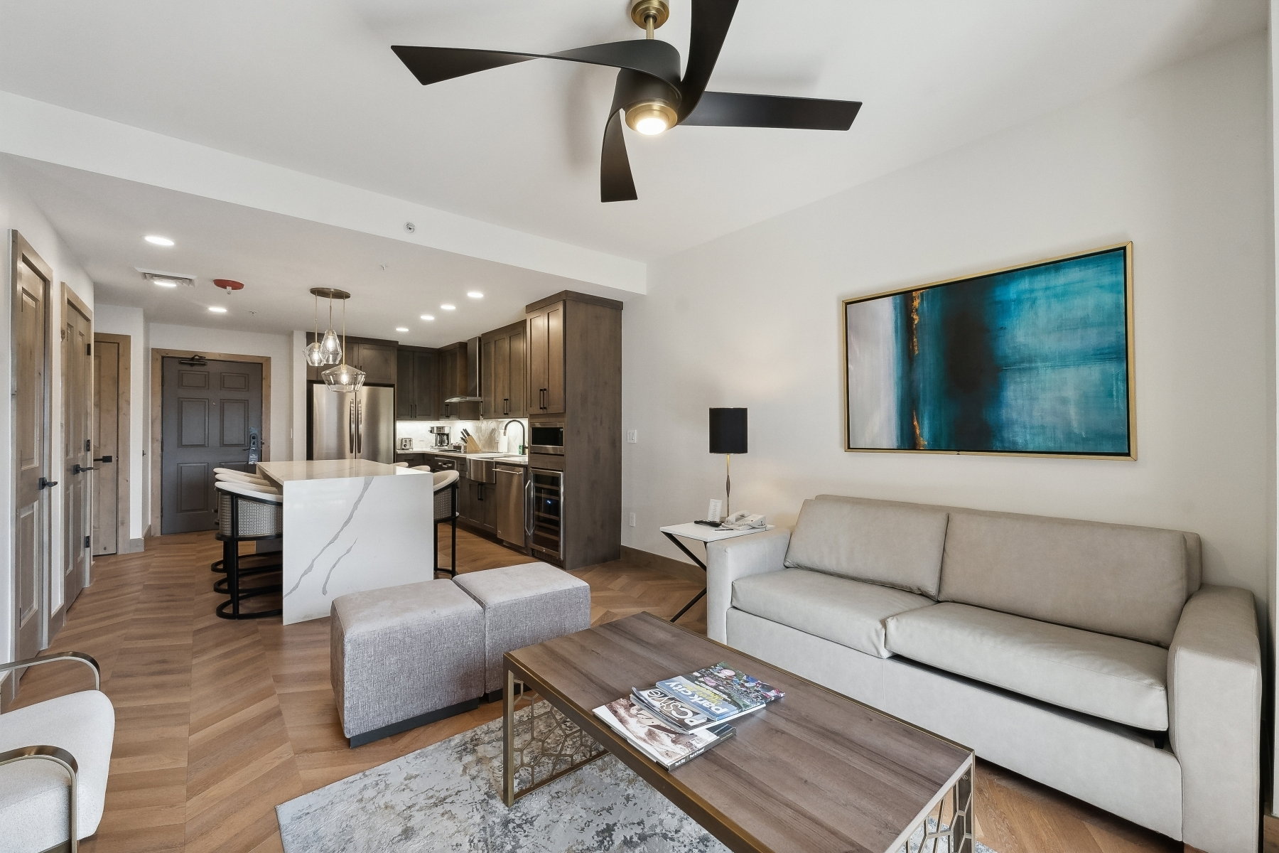 Open-concept living space featuring herringbone wood-finish flooring, a contemporary ceiling fan, and recessed lighting