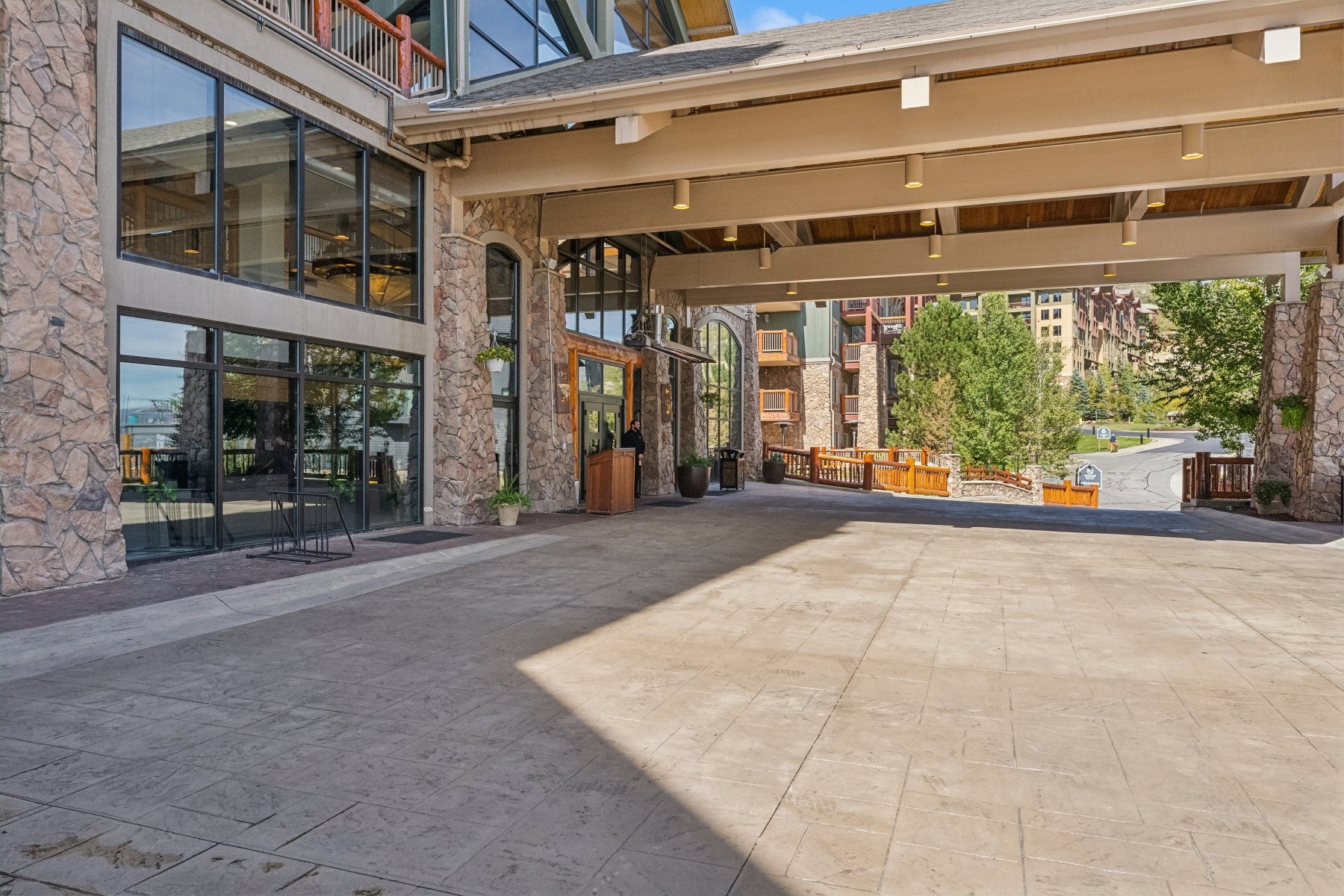 Stately stone veneer exterior with expansive window walls, a covered porte-cochère featuring recessed lighting, and a stamped concrete entrance