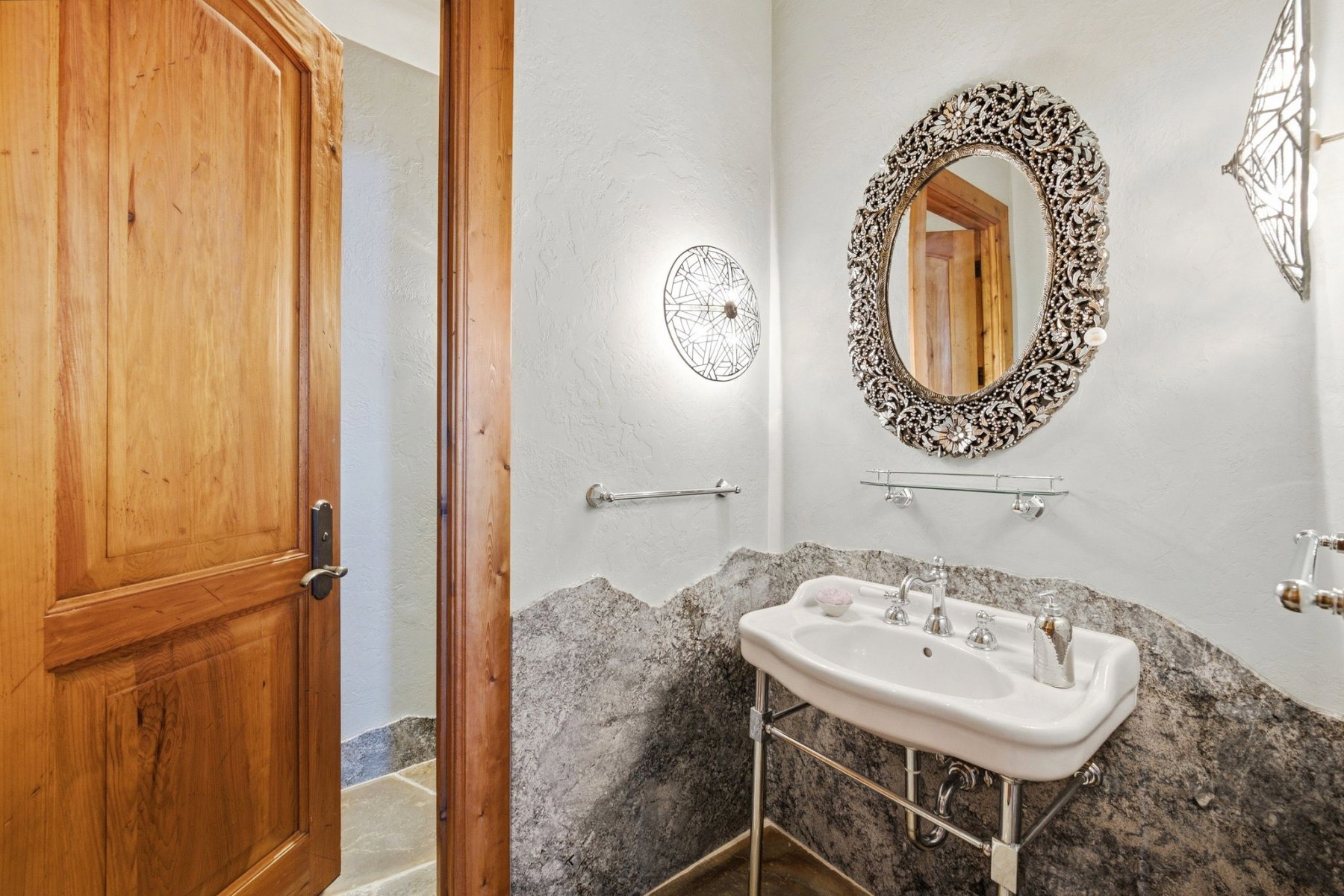 Pedestal sink with chrome fixtures and a decorative framed mirror
