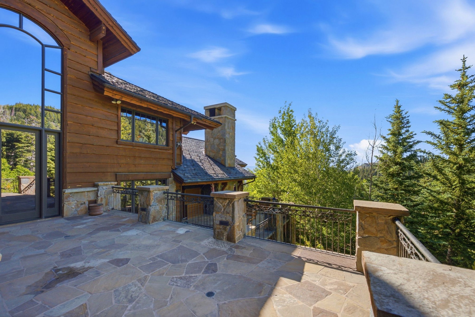 Stone patio featuring irregular flagstone paving and stone pillars with ornate metal railing