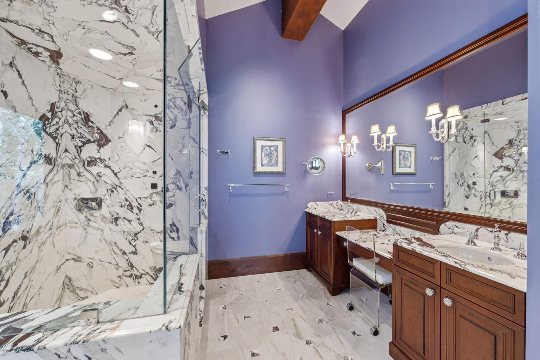 Spacious bathroom featuring a full-height marble shower enclosure with glass surround, double vanity with marble countertops, and an integrated dressing table