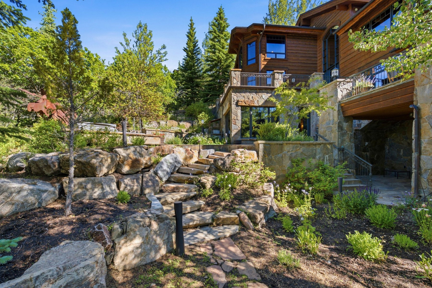 Multi-level stone retaining walls featuring natural rock steps, mature trees, and landscaping