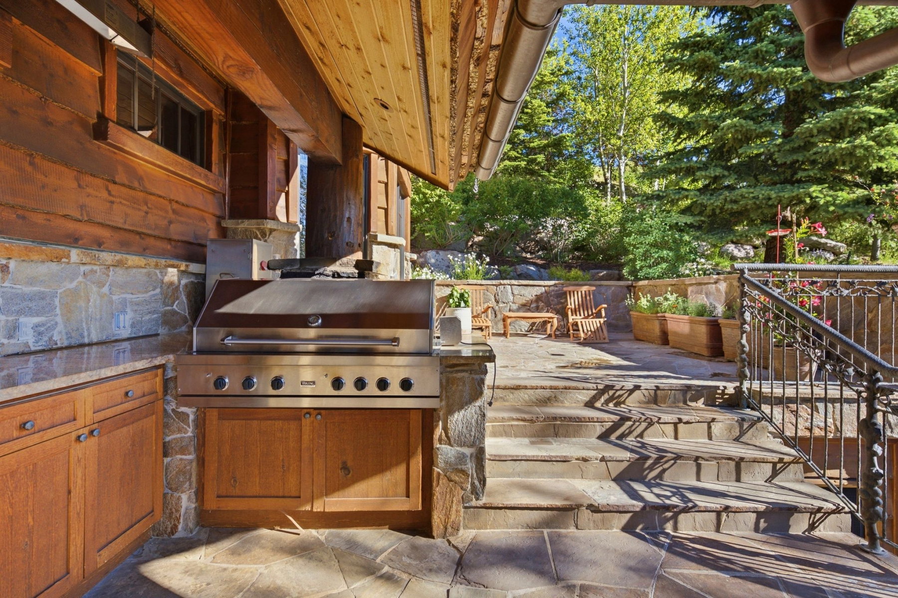 Outdoor kitchen featuring a stainless steel grill, wood cabinetry, and stone countertop