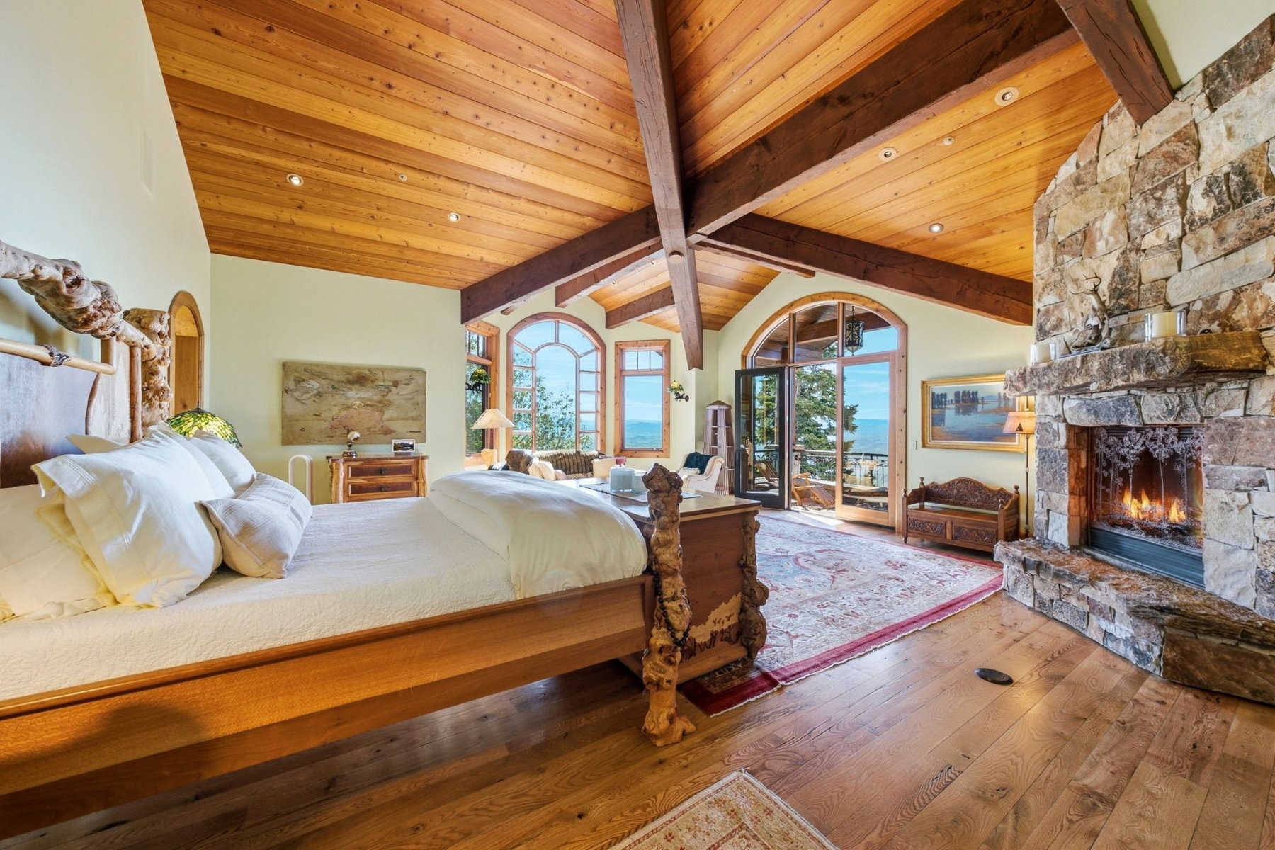 Vaulted wood-paneled ceiling with exposed beams, stone fireplace, and wood-finish flooring