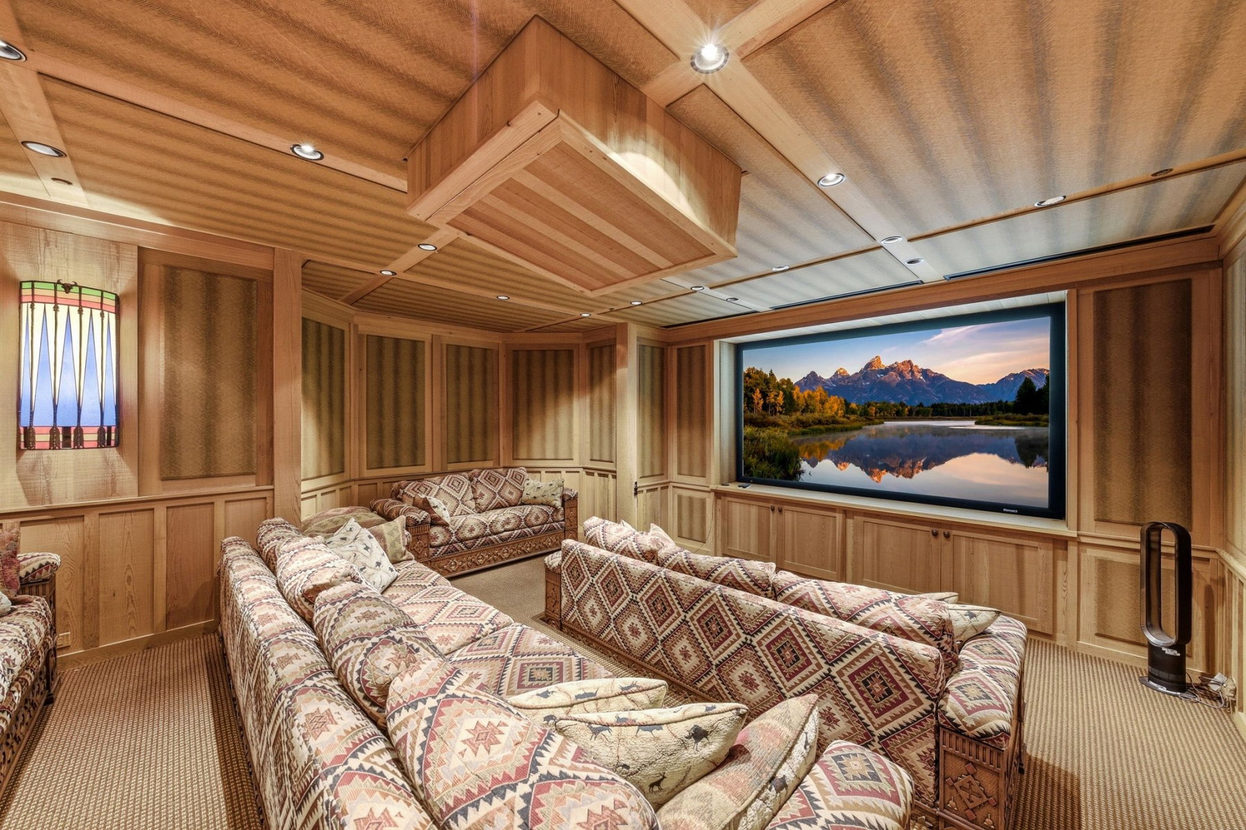 Dedicated media room featuring a large projection screen, recessed lighting, wood-paneled walls, and built-in cabinetry