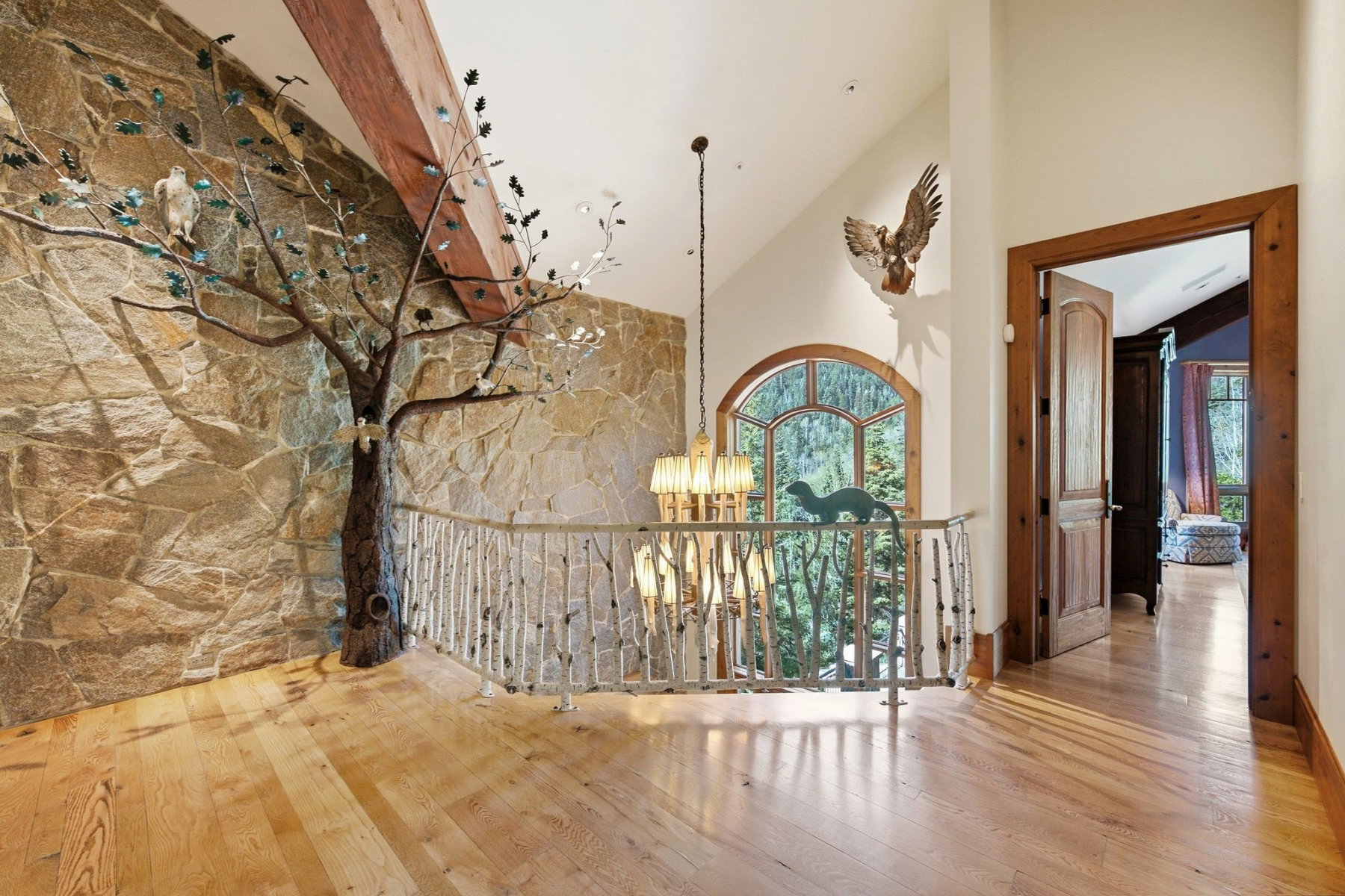 Stone accent wall featuring a decorative tree sculpture and exposed wood beam