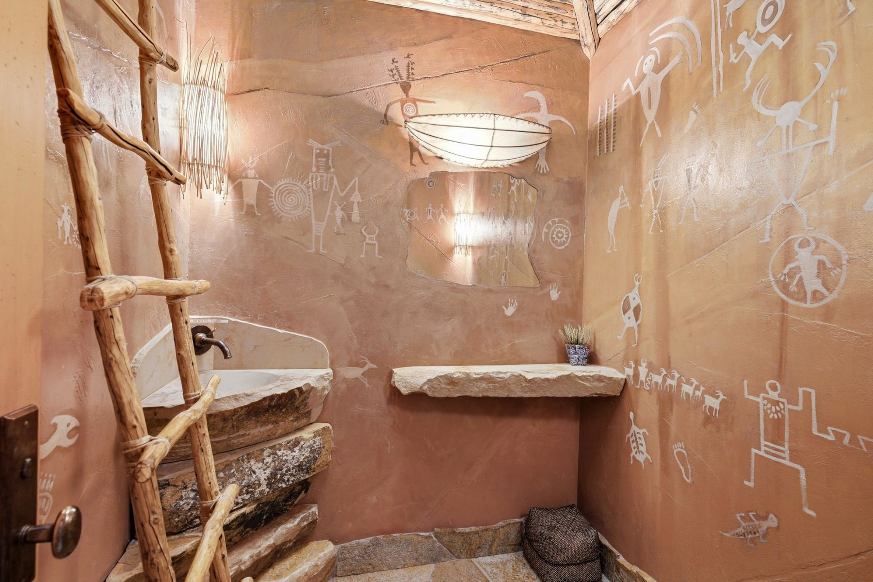 Custom bathroom with a stone basin sink, integrated faucet, and a decorative ladder accent