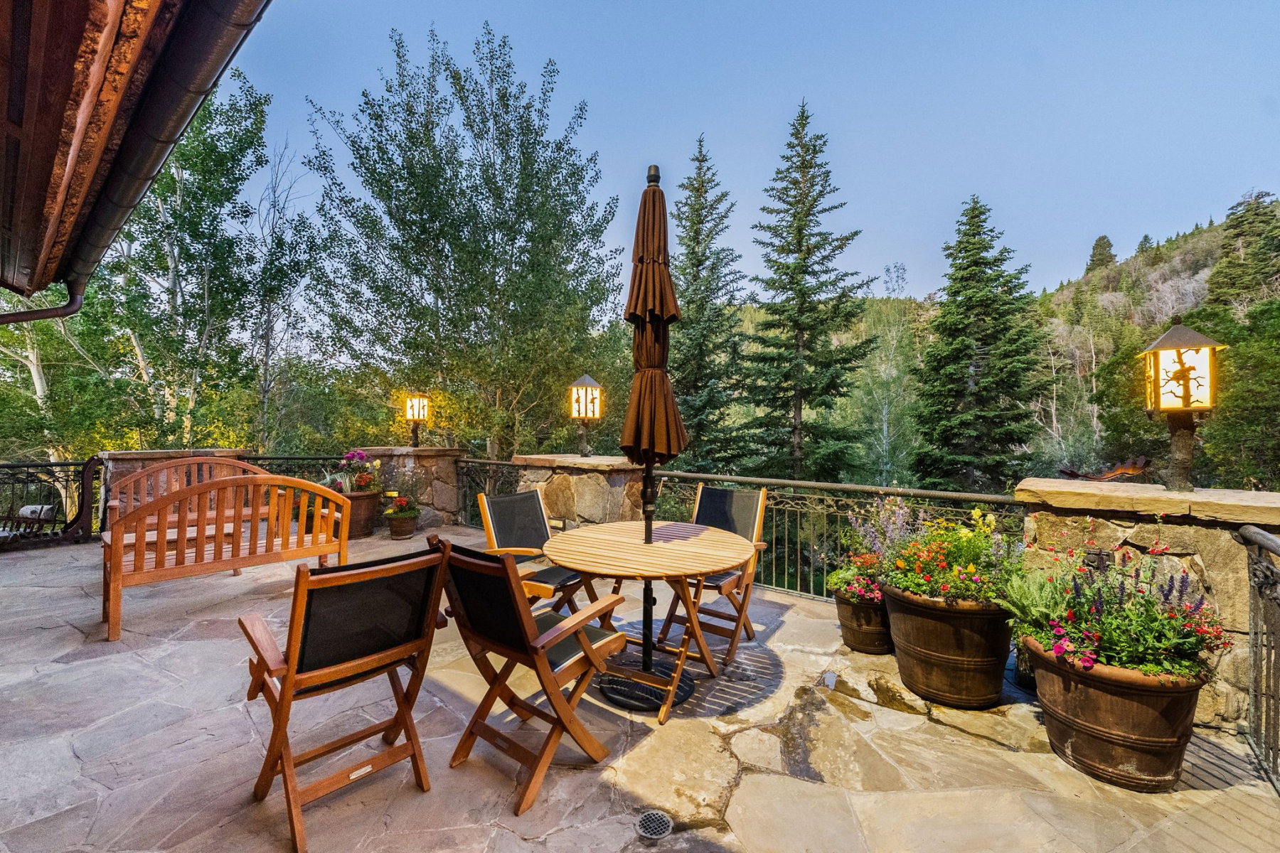 Expansive flagstone patio with a stone retaining wall and metal railing
