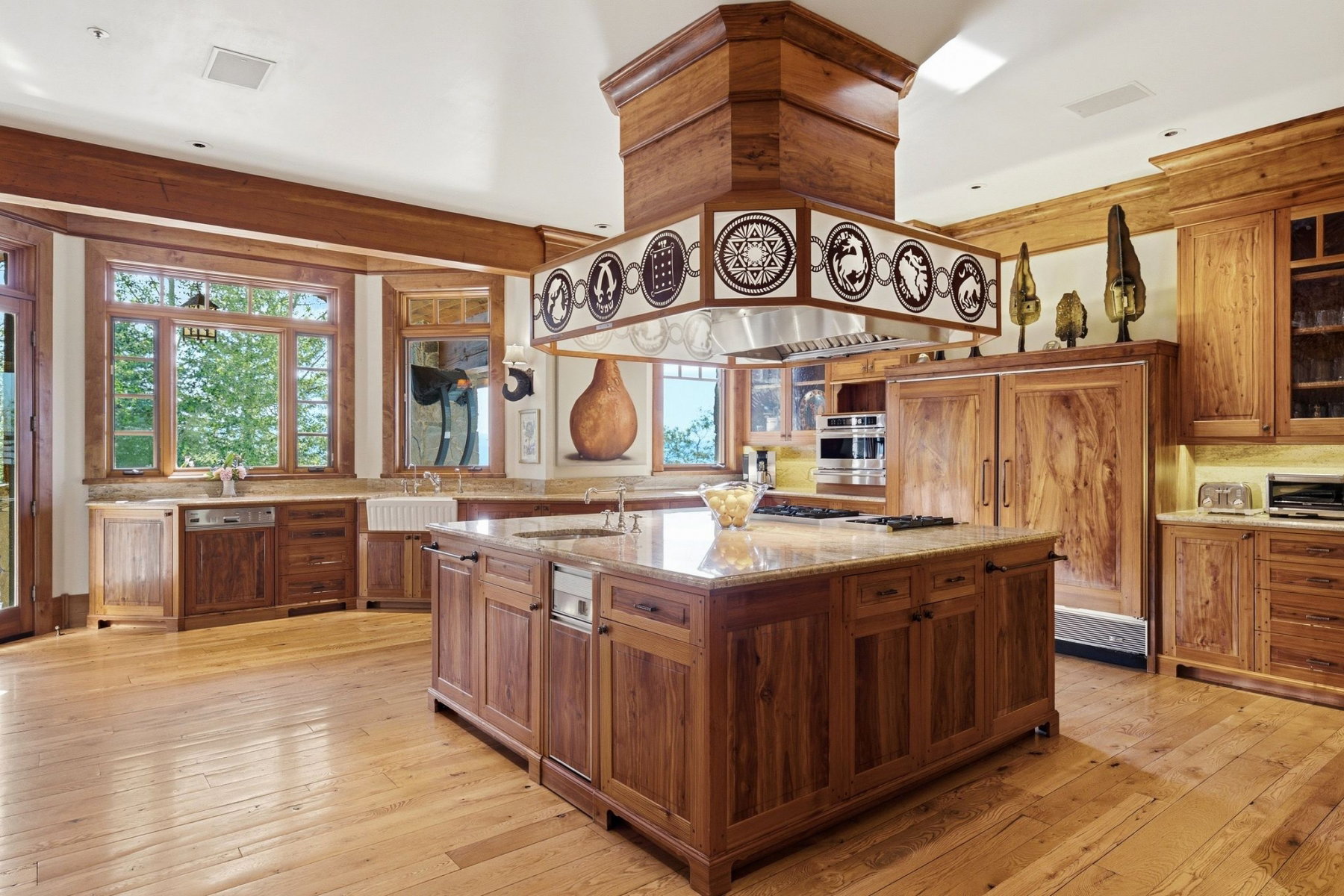 Spacious kitchen featuring an expansive central island with a built-in cooktop, integrated dishwasher, and granite countertops
