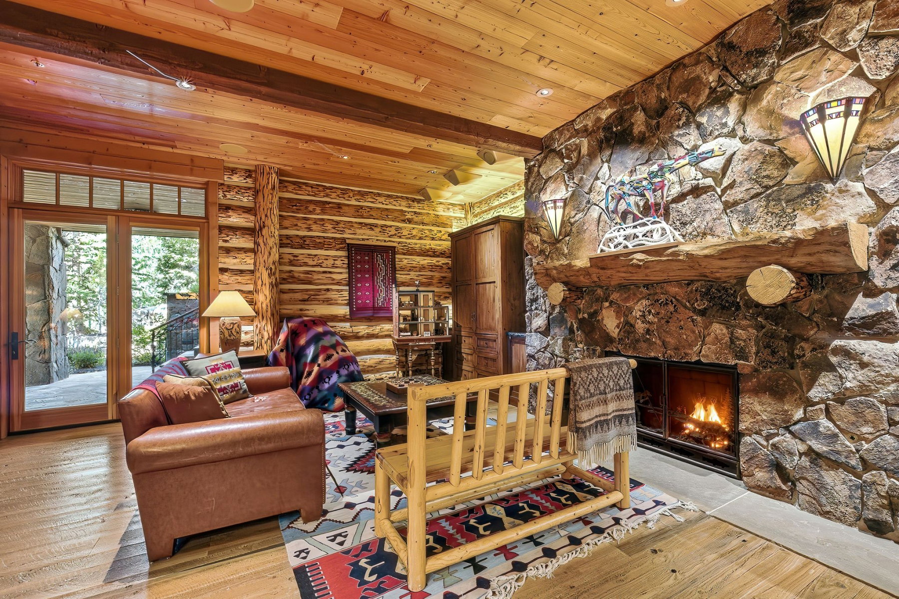 Stone fireplace featuring a rustic wood mantel and sconce lighting