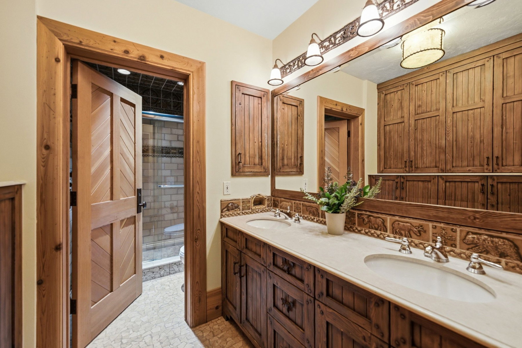 Double vanity with light-toned countertops and dual undermount sinks, set against a full-width mirror