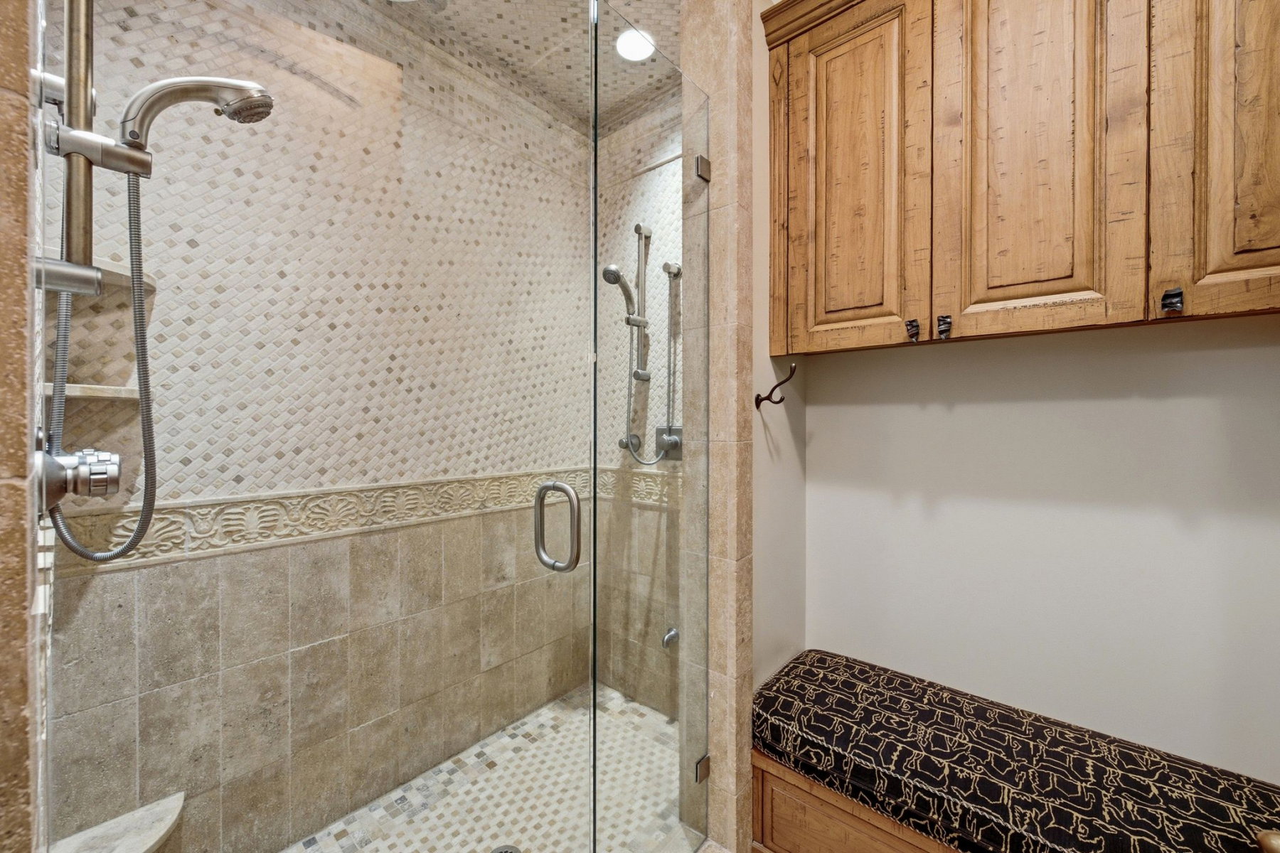 Glass-enclosed shower featuring a handheld showerhead and patterned tile work