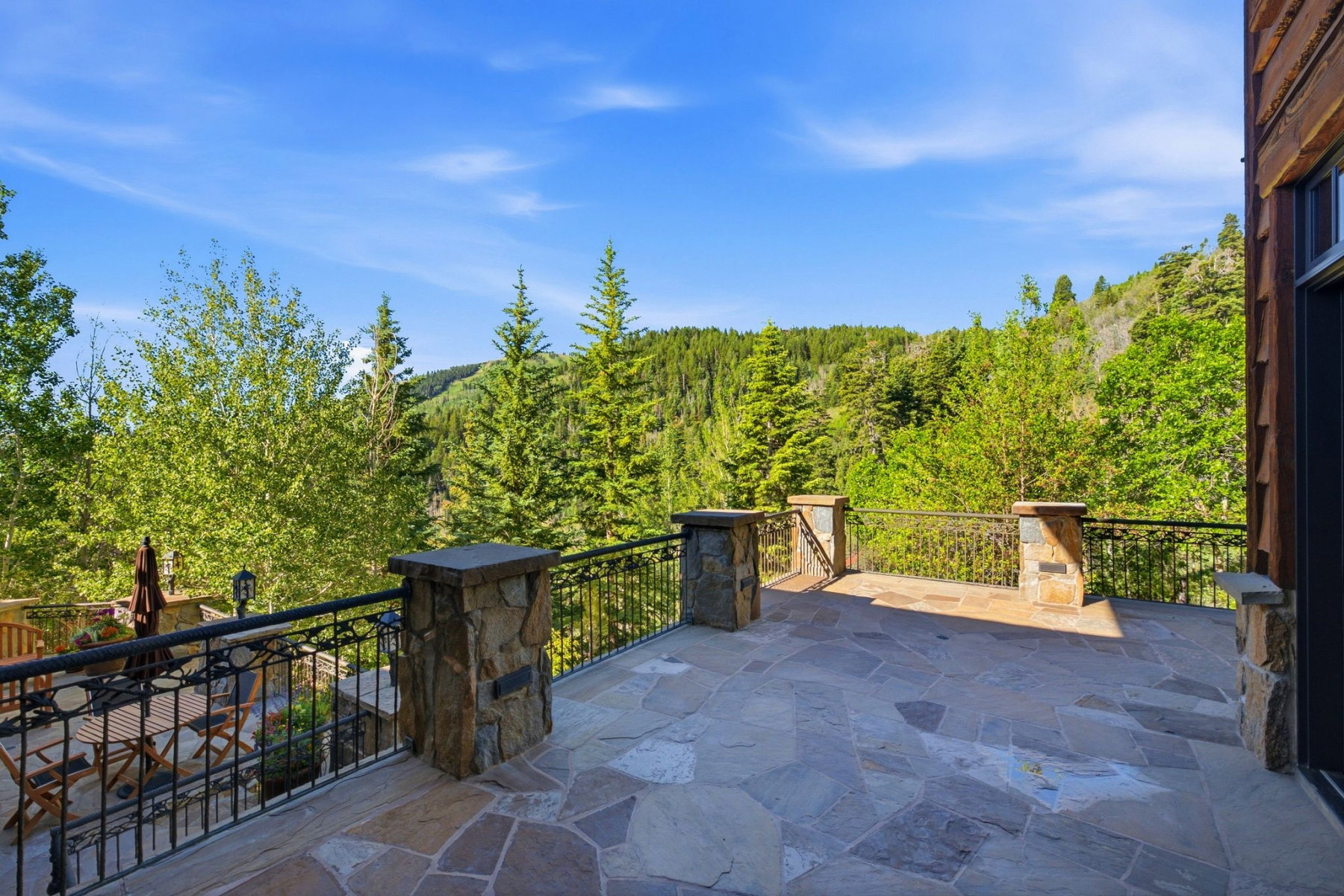 Expansive flagstone patio with wrought iron railings and stone pillars