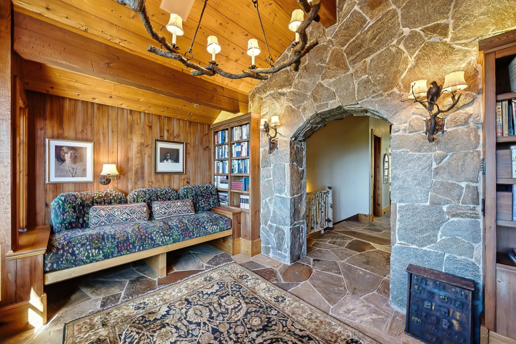 Stone archway entrance featuring flagstone flooring, wood-paneled walls, and built-in shelving