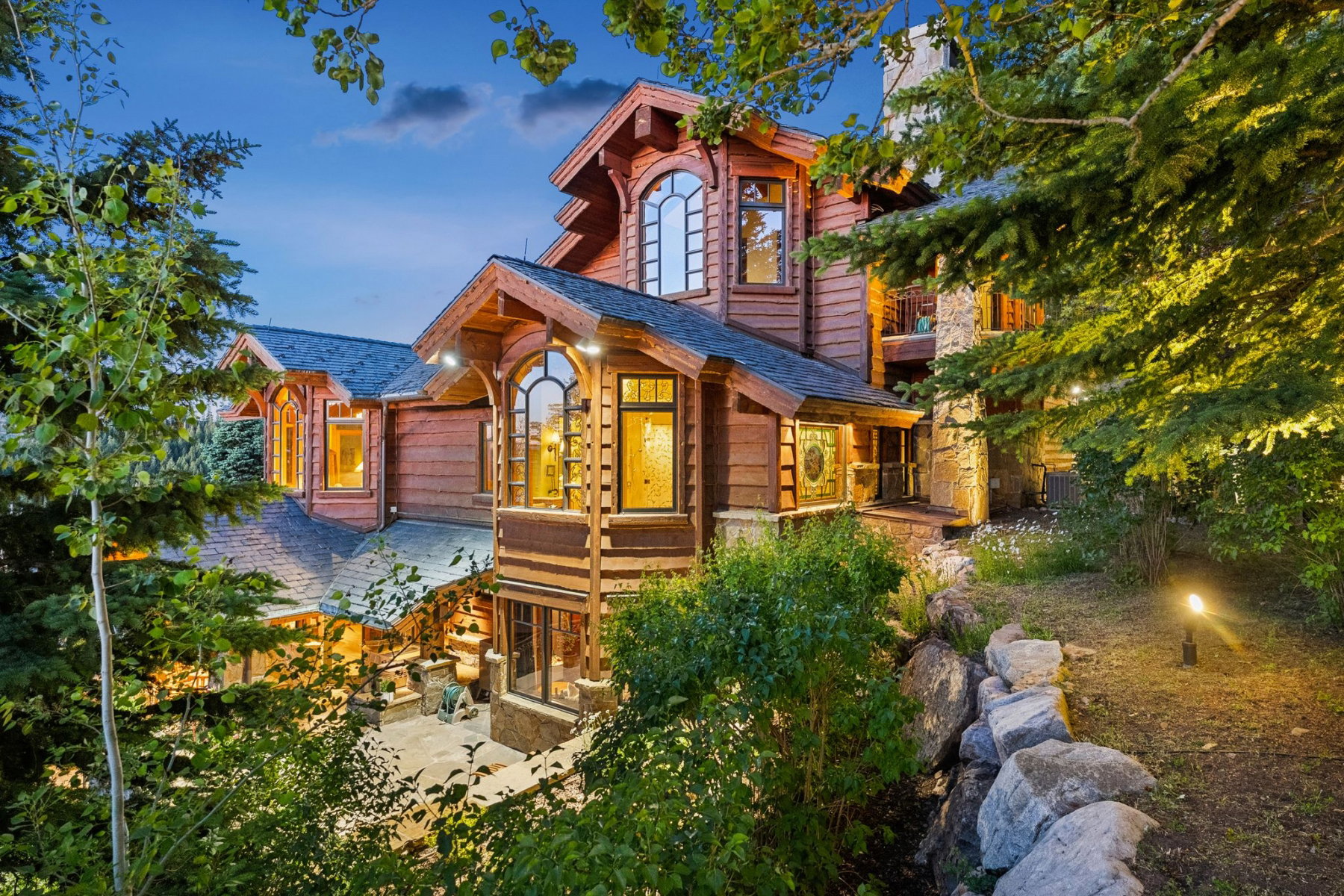 Multi-level wood-sided exterior featuring stone accents, gabled roofs, and arched windows