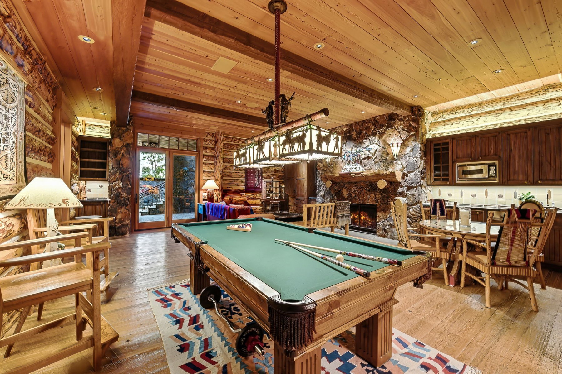 Recreational space featuring a pool table, stone fireplace, wood-finish flooring, and built-in wet bar with wood cabinetry and an integrated microwave