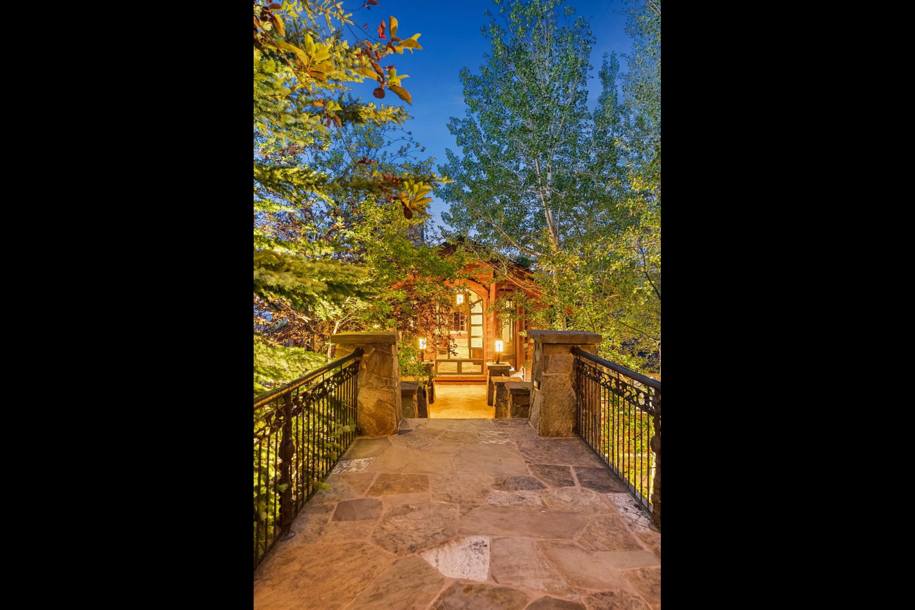 Stone flagstone path leading to a property entrance, flanked by wrought iron railings with stone posts