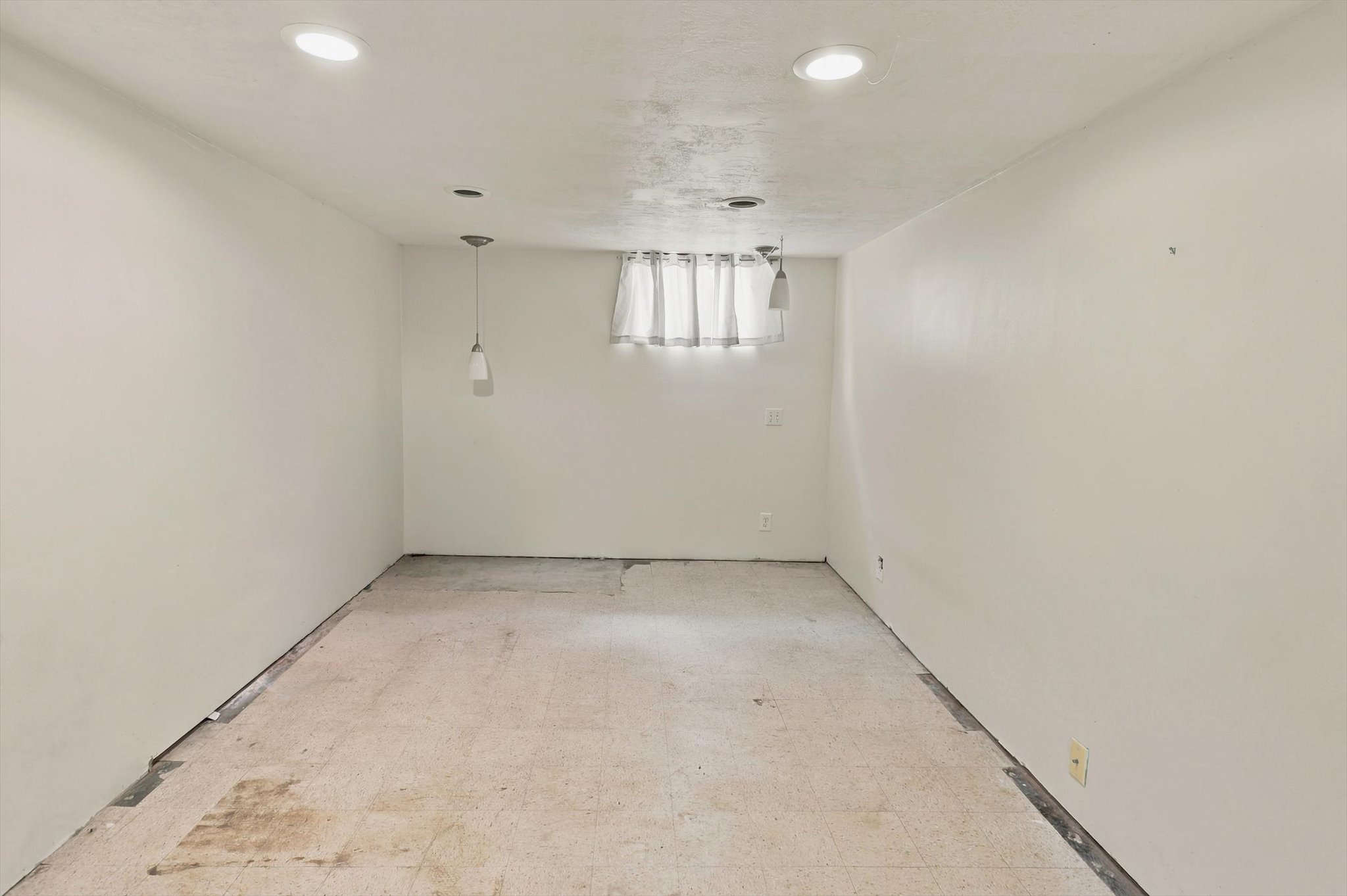 Room featuring white painted walls and a window with light-filtering curtains