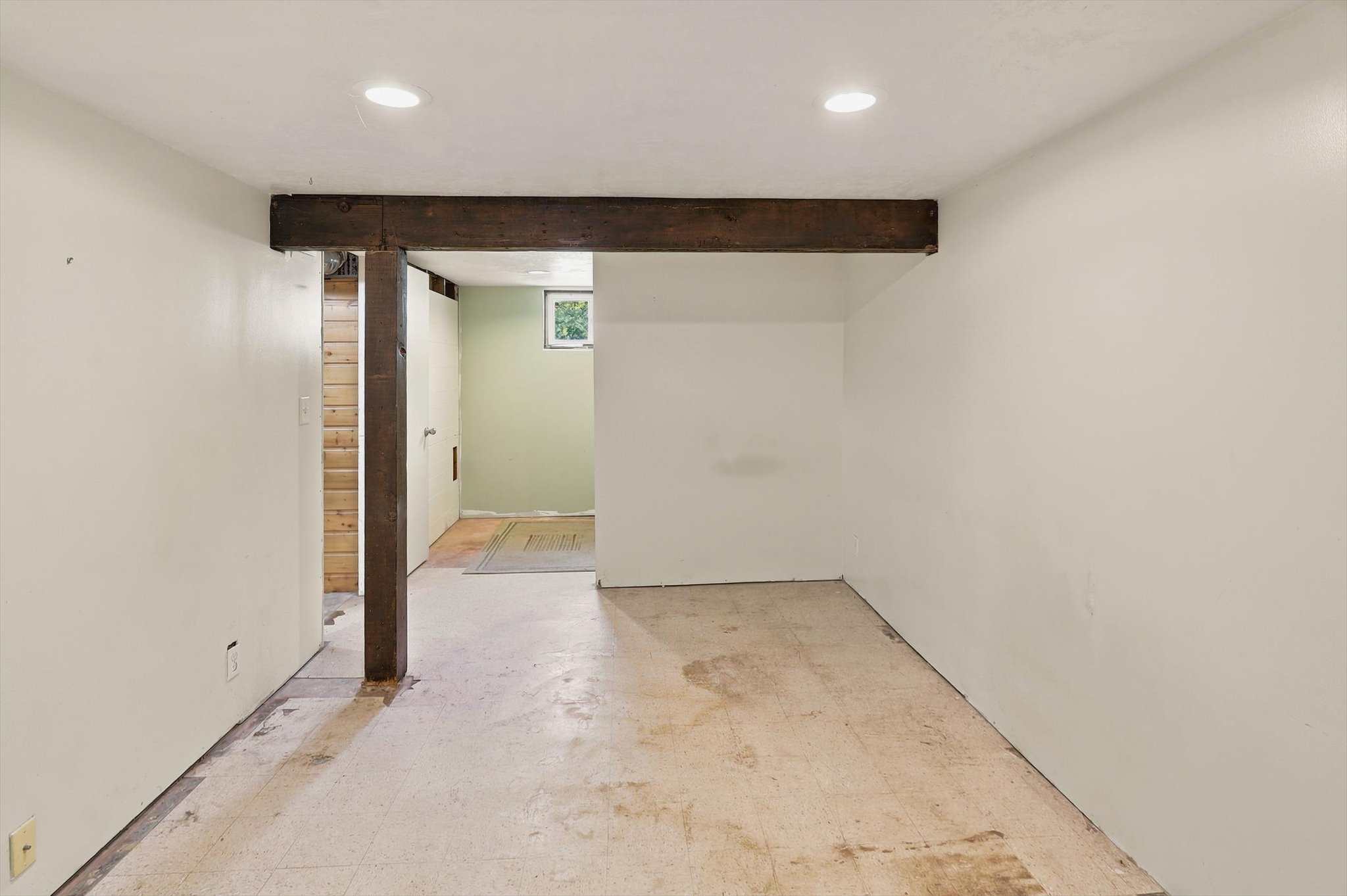 Lower level space featuring exposed wood beam, recessed lighting, and a visible window