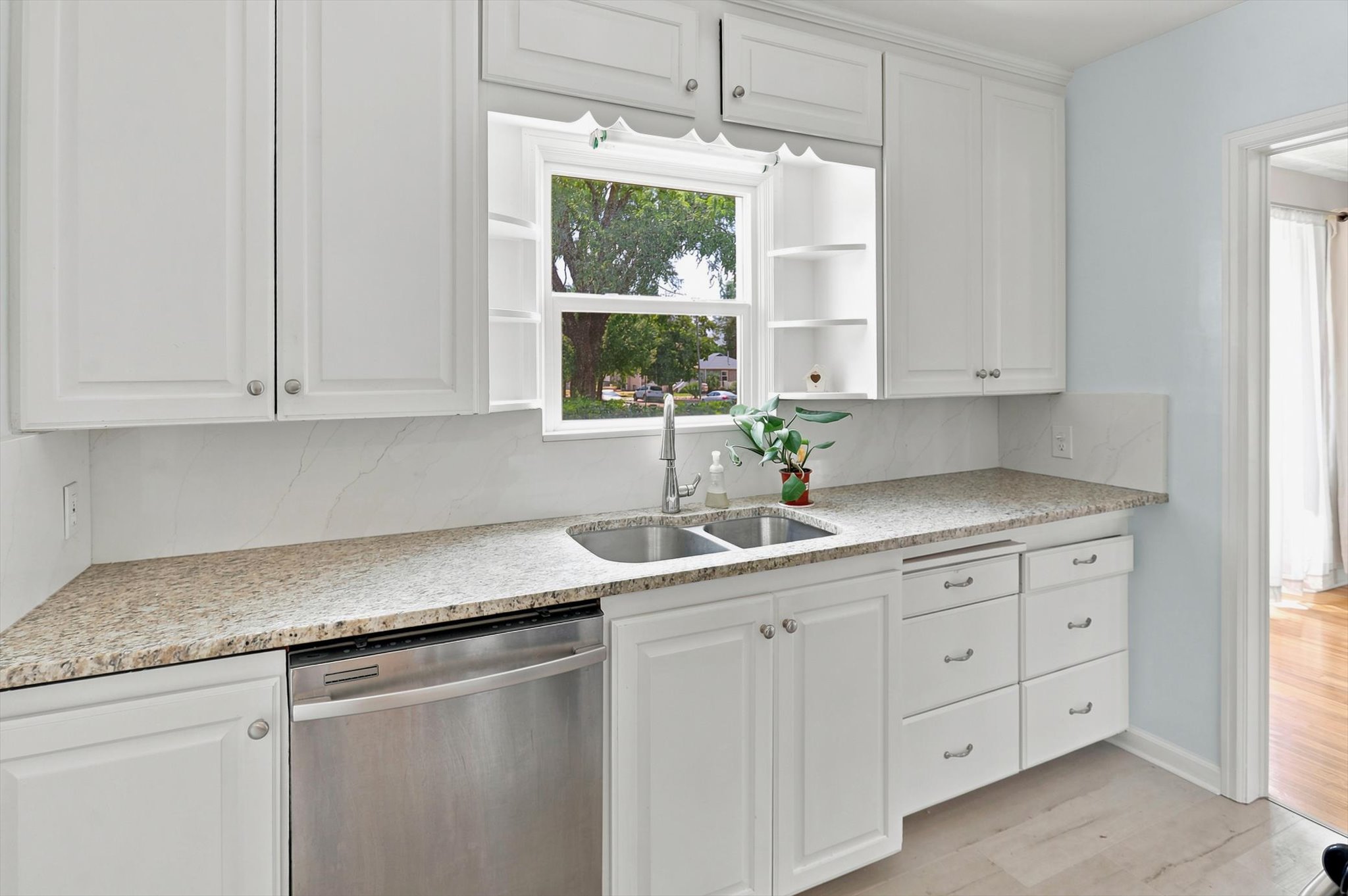 Kitchen featuring white shaker cabinetry, speckled countertops, a stainless steel double basin sink, and a built-in stainless steel dishwasher