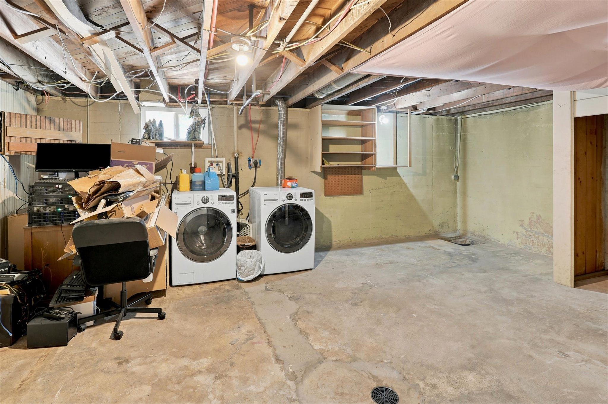 Basement space featuring exposed ceiling joists, concrete flooring, and a small window