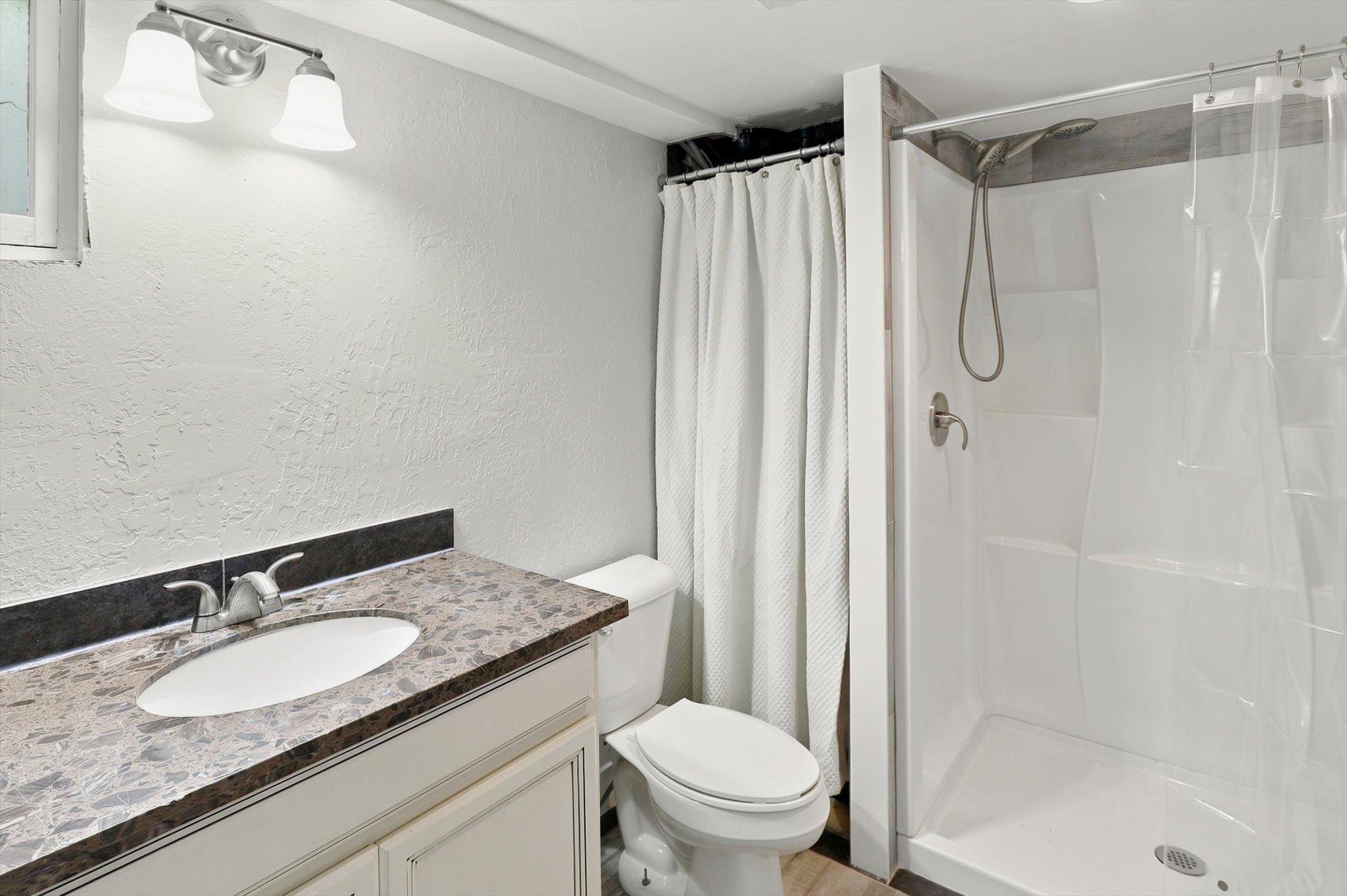 Bathroom featuring a single vanity with a patterned countertop, undermount sink, and brushed nickel faucet