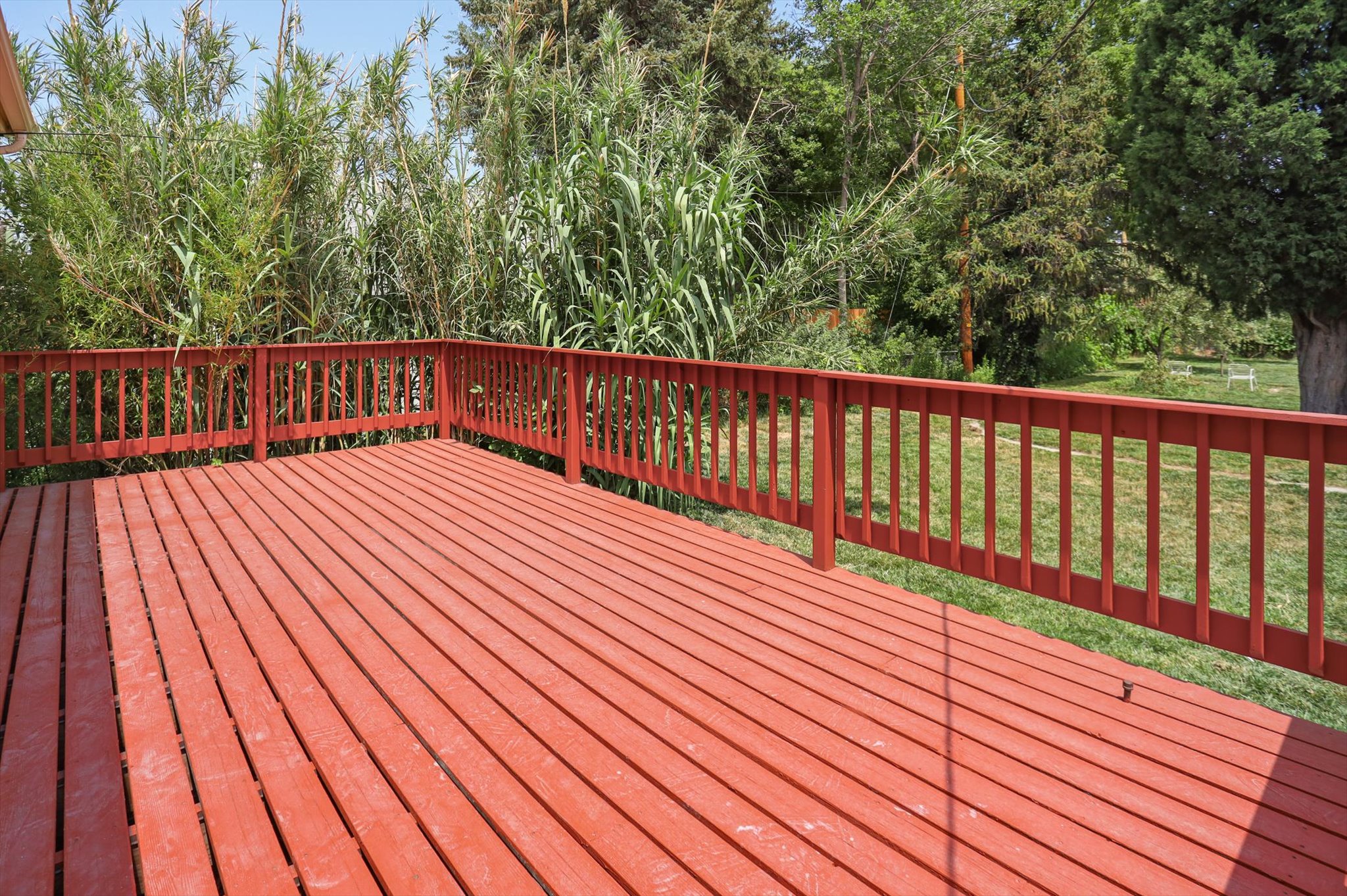 Expansive red-stained wood deck featuring a matching railing system
