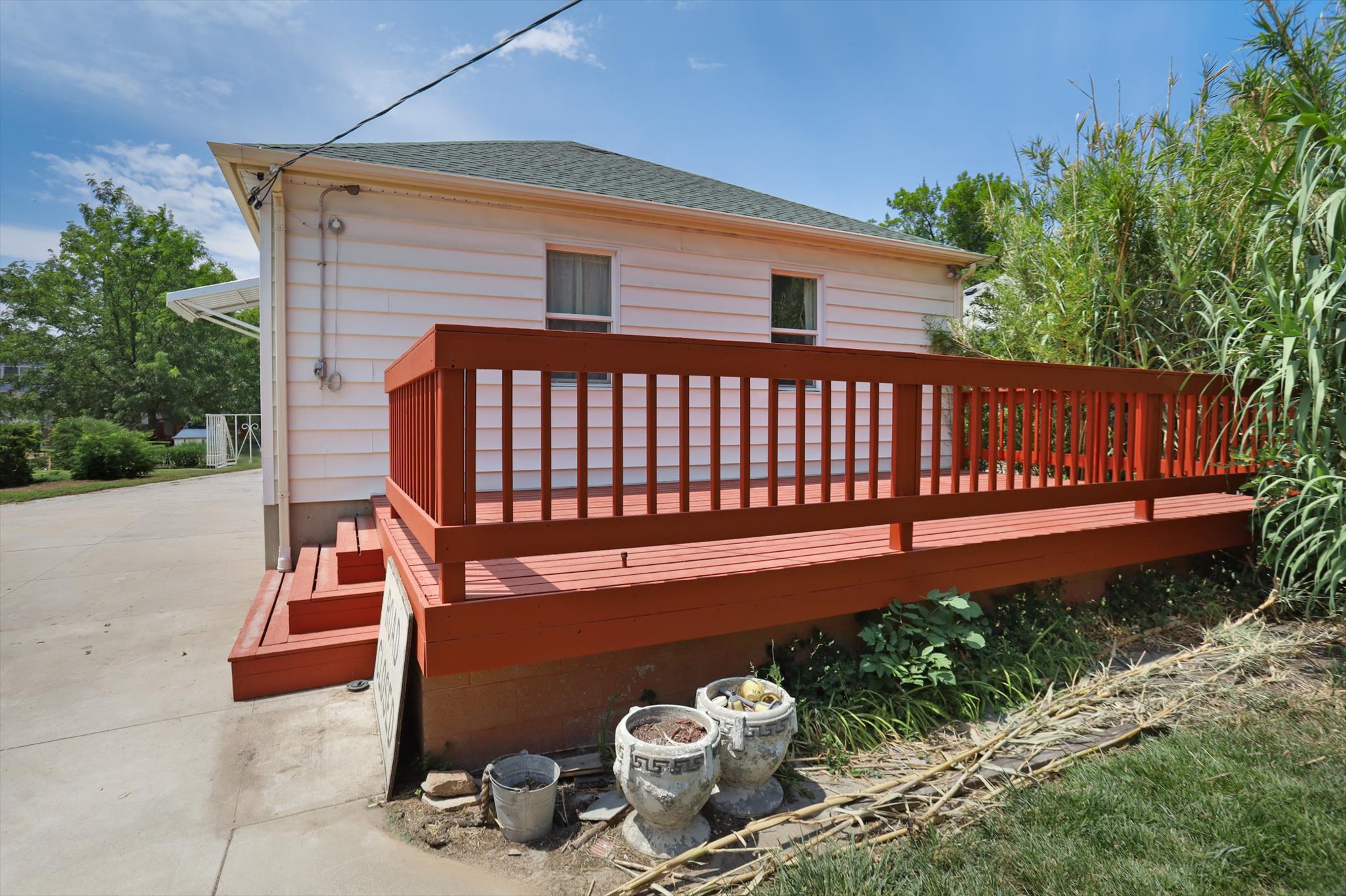 Red-stained deck with railing and steps, contrasting with white siding