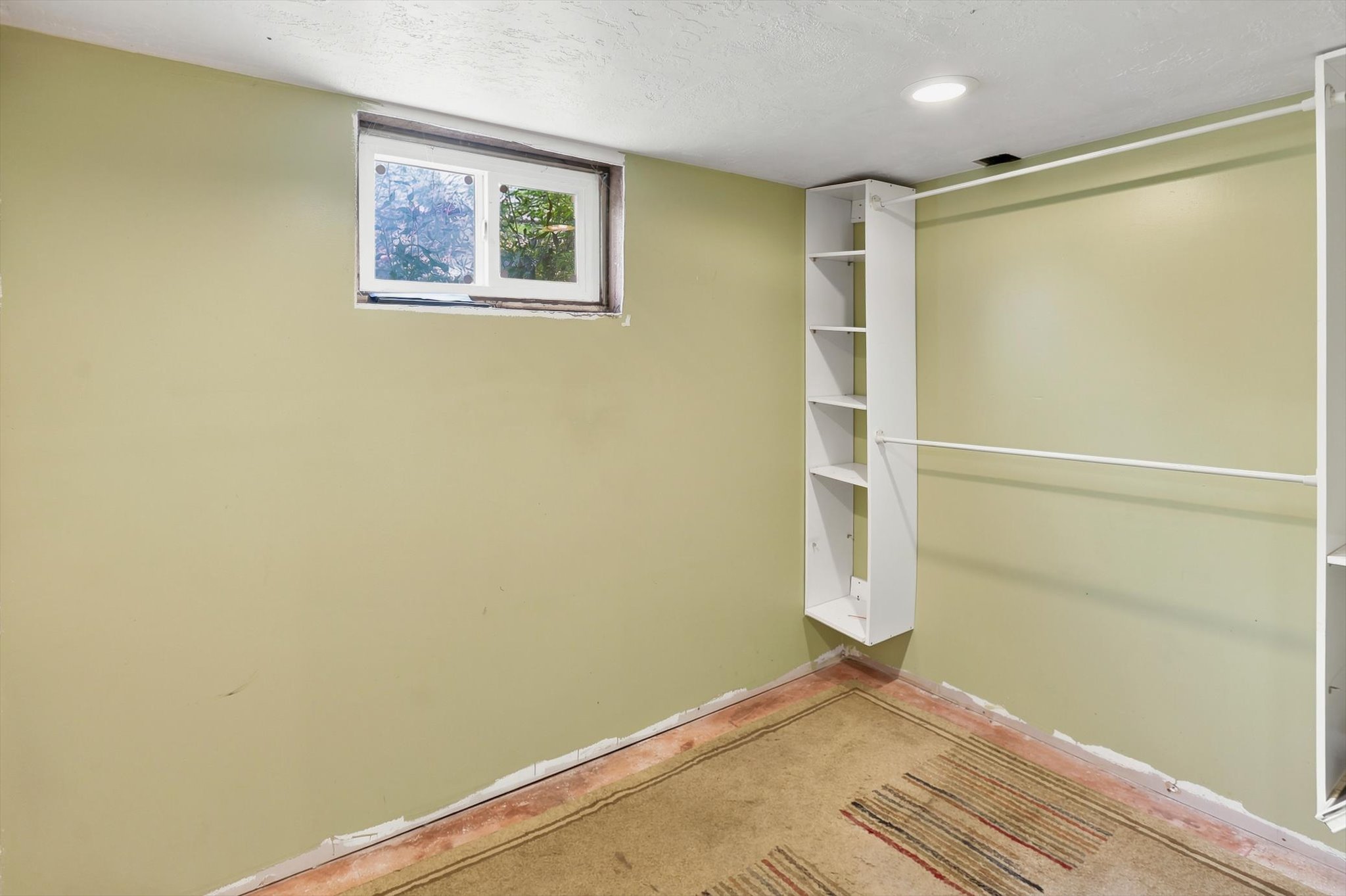 Room with a single window, recessed lighting, and built-in white shelving