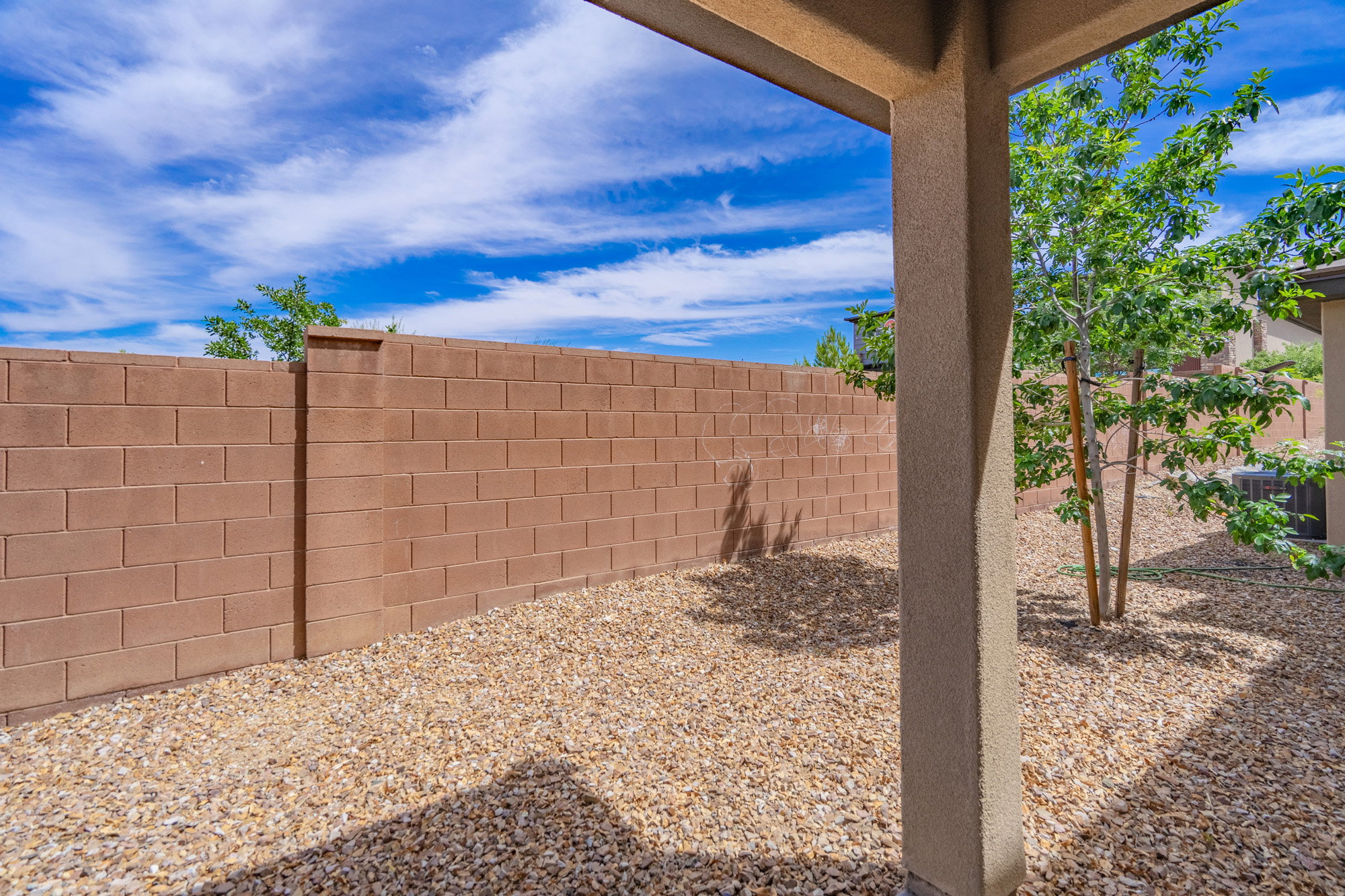 Covered patio area with a textured stucco support column, featuring a gravel ground cover