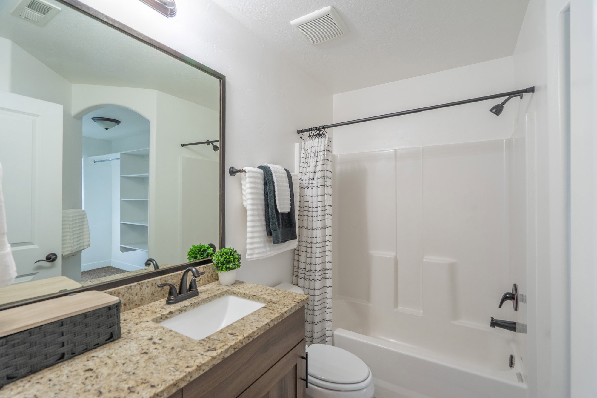 Bathroom featuring a single vanity with a granite countertop, undermount sink, and matte black faucet