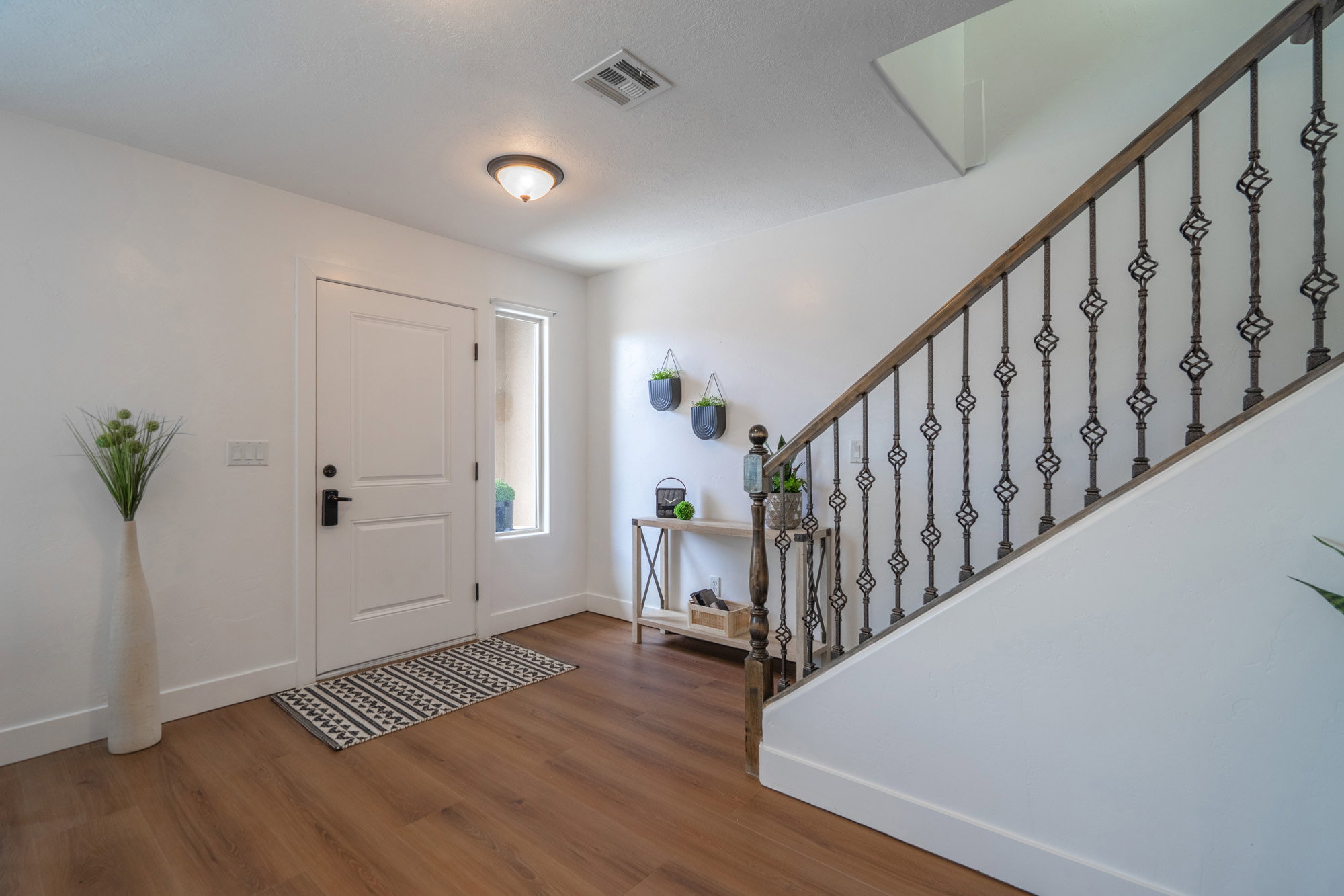 Entryway featuring wood-finish flooring, a white paneled door with black hardware, and a sidelight window