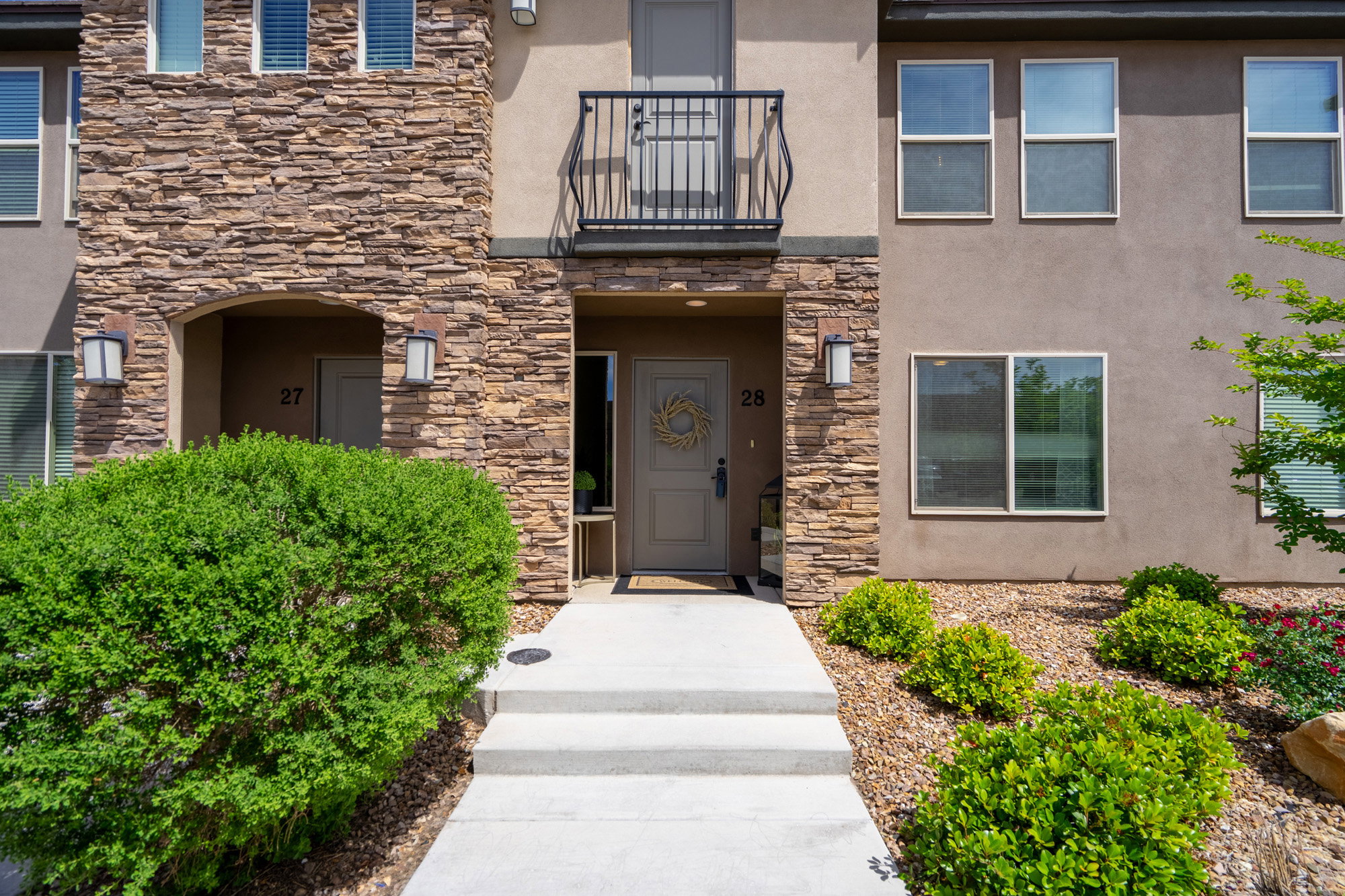 Multi-story building facade featuring stacked stone accents and a stucco finish