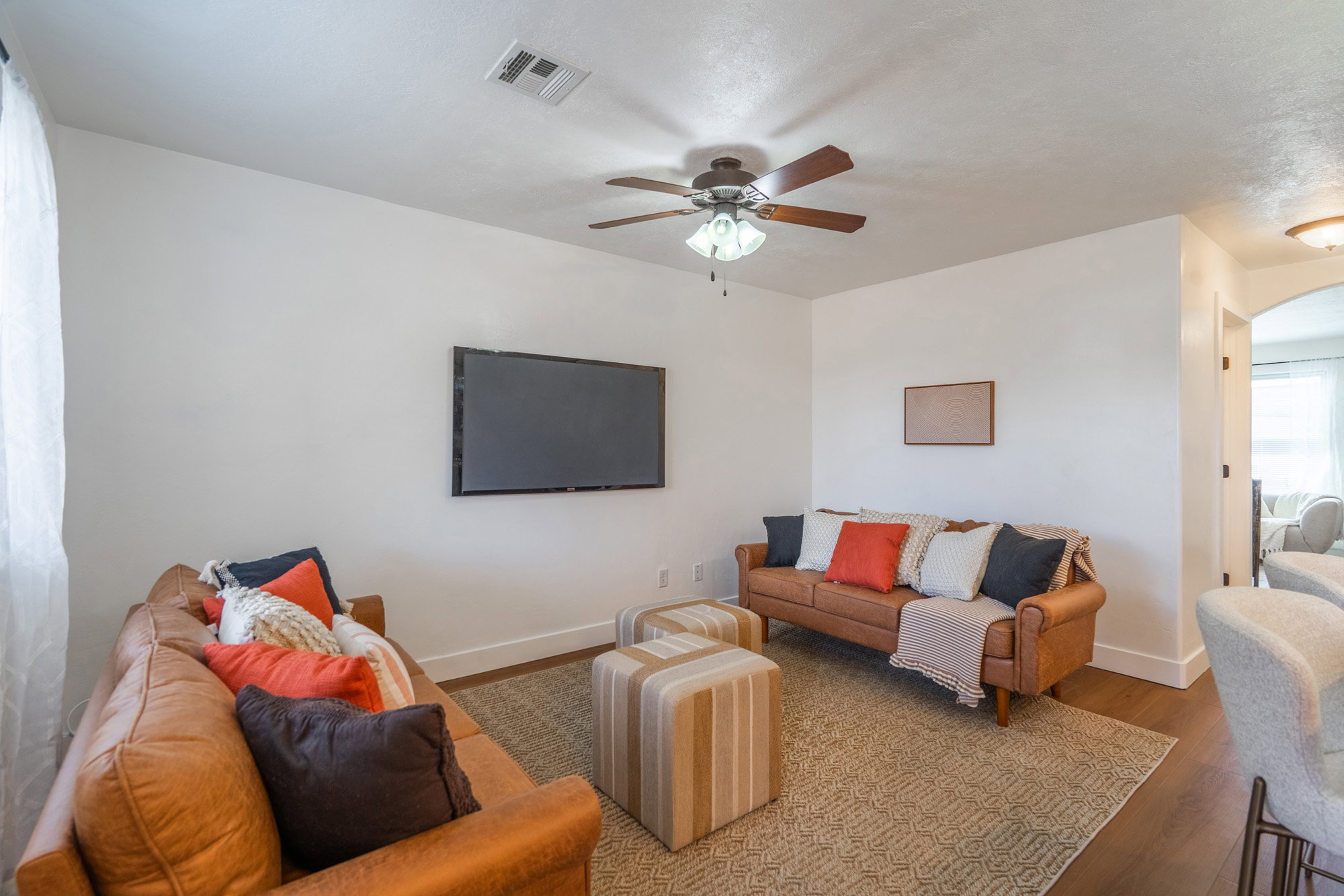 Living area featuring wood-finish flooring, a ceiling fan with light fixture, and an arched doorway