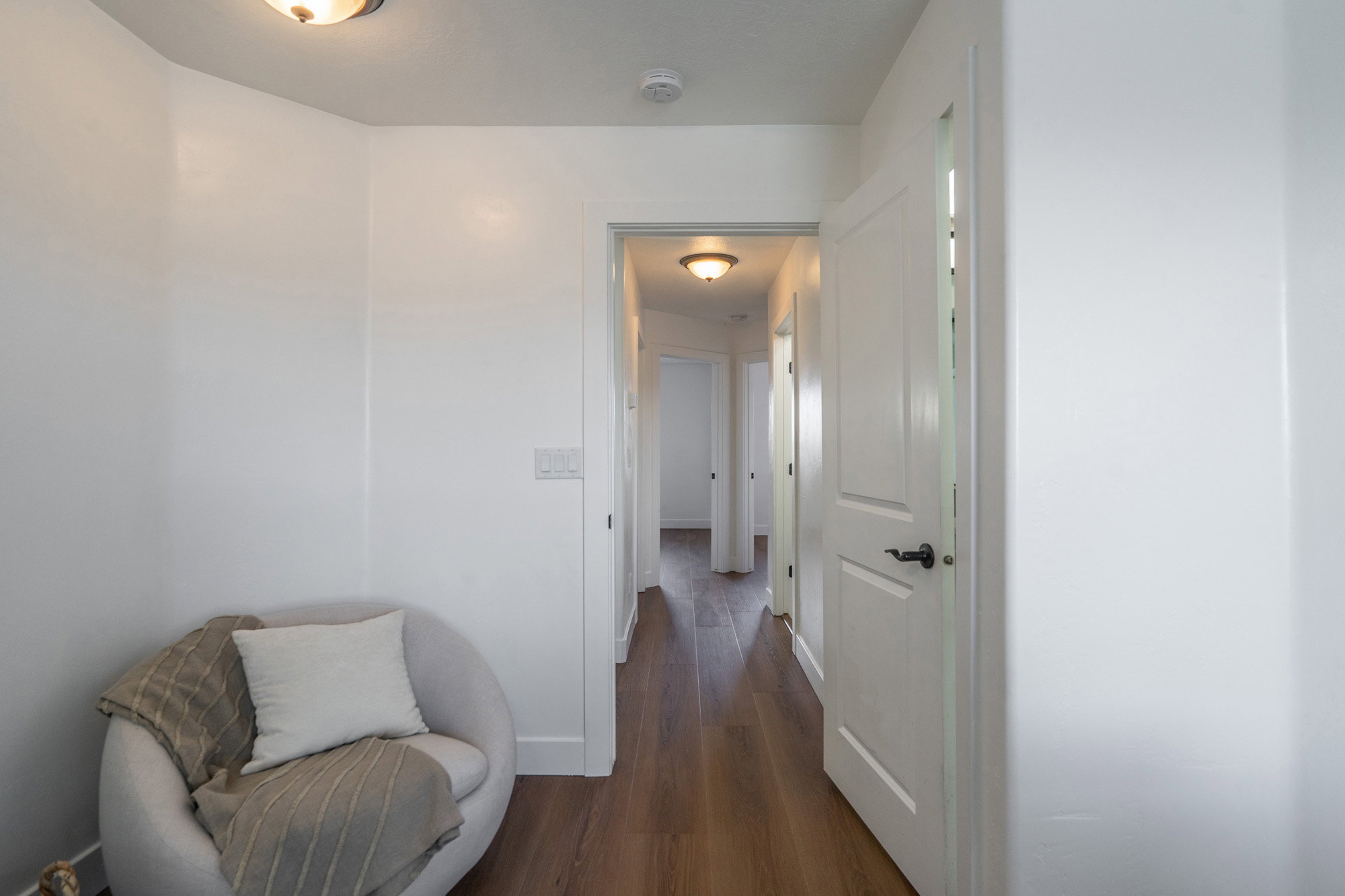Bright hallway featuring wood-finish flooring, white walls, and recessed lighting fixtures
