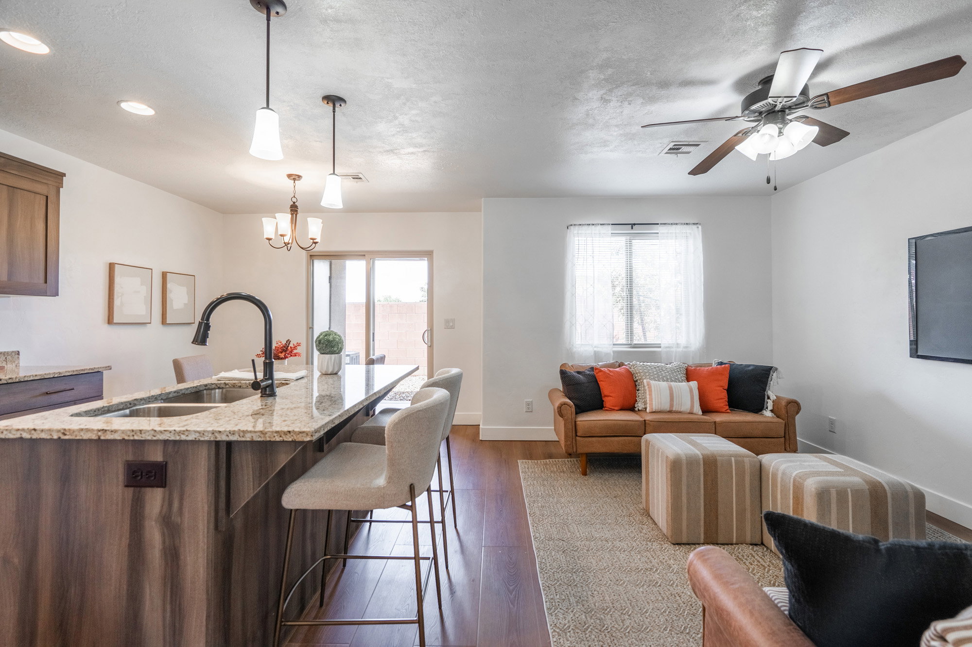 Open-concept living area featuring a kitchen island with granite countertops and seating, wood-finish flooring, and recessed lighting