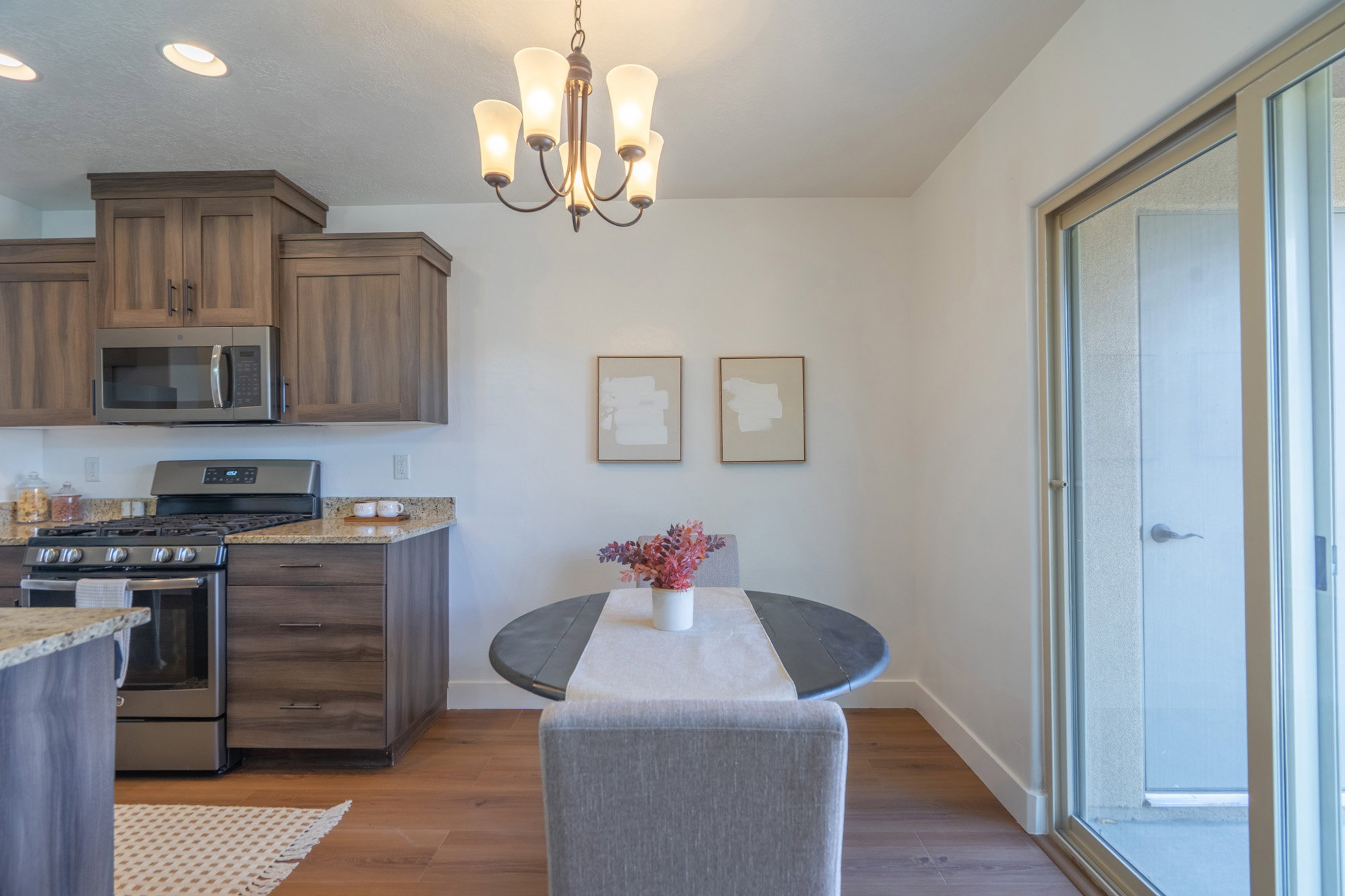 Open-concept kitchen and dining area featuring wood-finish flooring, recessed lighting, and a five-light chandelier