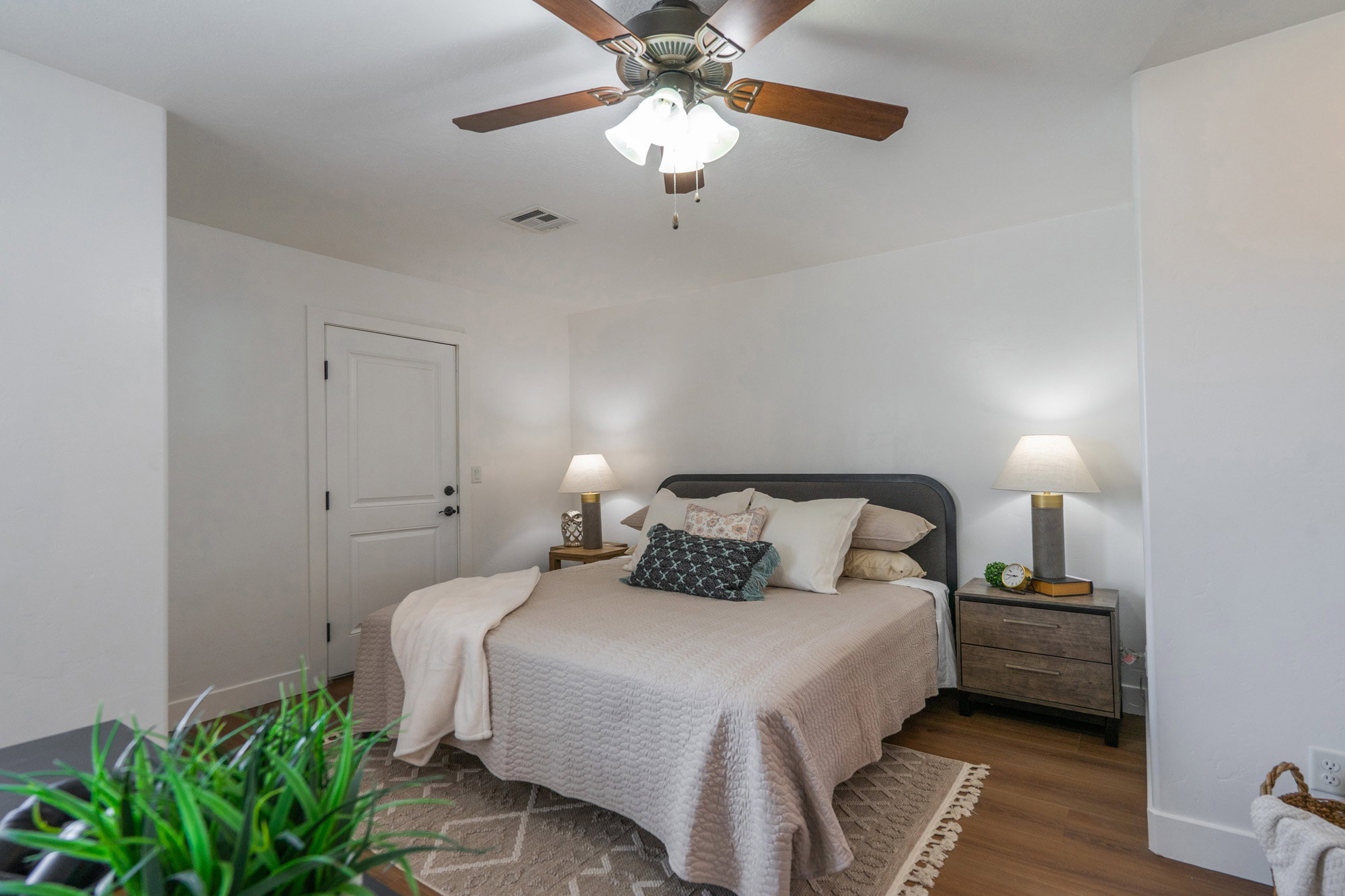 Bedroom featuring wood-finish flooring, a ceiling fan with integrated lighting, and a white paneled door