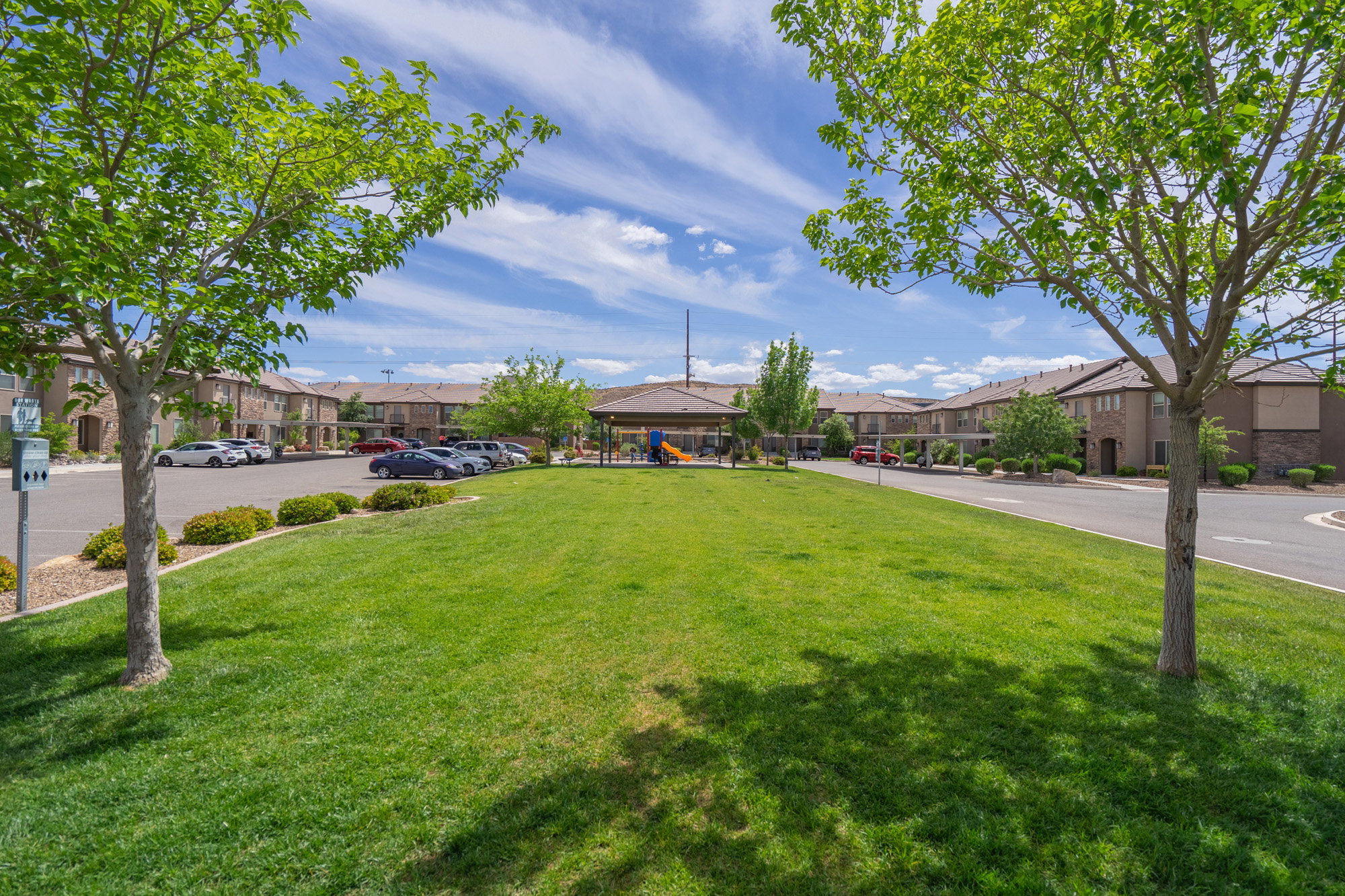 Expansive green lawn area featuring mature trees, a covered gazebo, and a play structure
