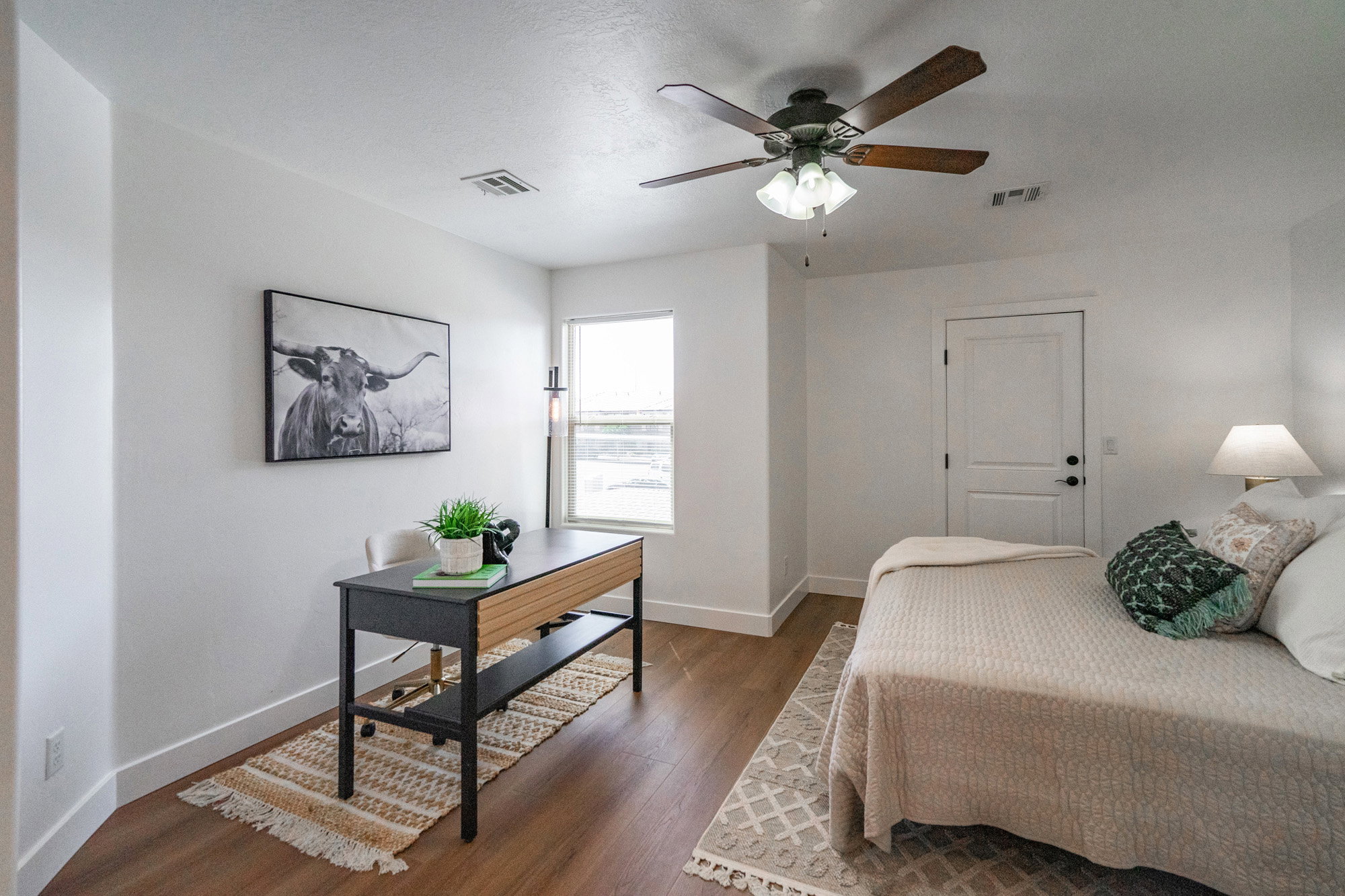 Bright interior space featuring wood-finish flooring, a ceiling fan with integrated lighting, white baseboards, a white paneled door, and a single window