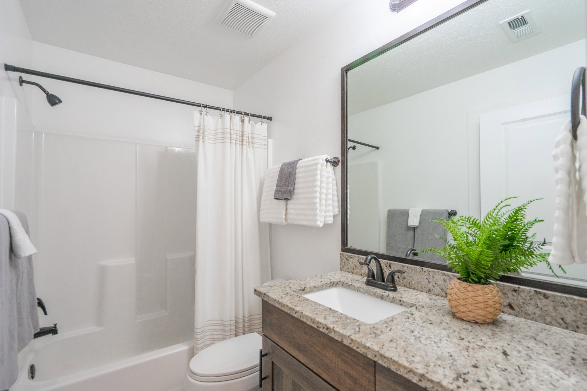 Bathroom featuring a vanity with a granite-style countertop, a rectangular undermount sink, and dark bronze fixtures