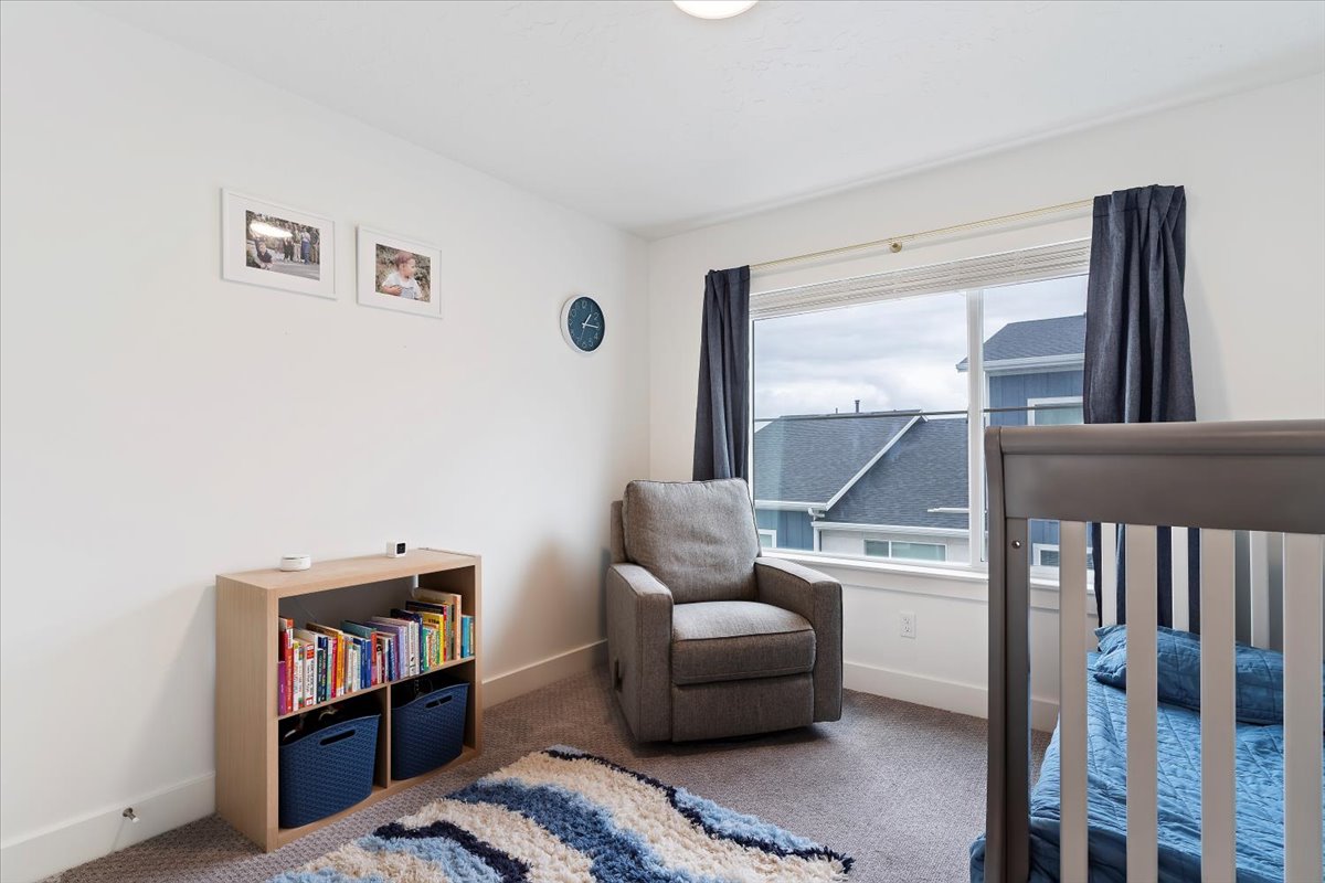 Bedroom featuring a large window, neutral-toned carpeting, white baseboards, and white wall finishes